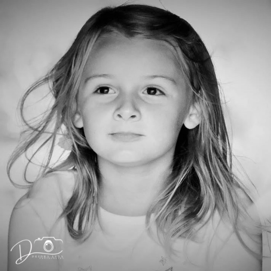 Black and white portrait of a young girl with shoulder-length hair, gazing softly at the camera.