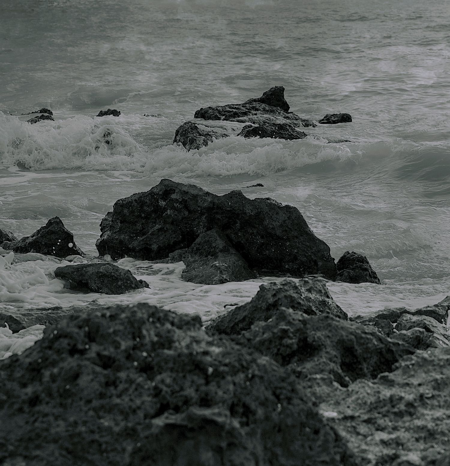 Dark rocky coastline with crashing ocean waves on a moody overcast day.