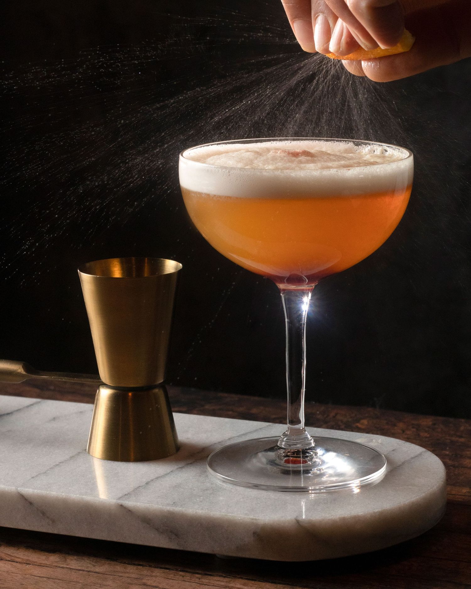 Close-up image of oils being squeezed from orange zest over a cocktail, beverage photography in Philadelphia