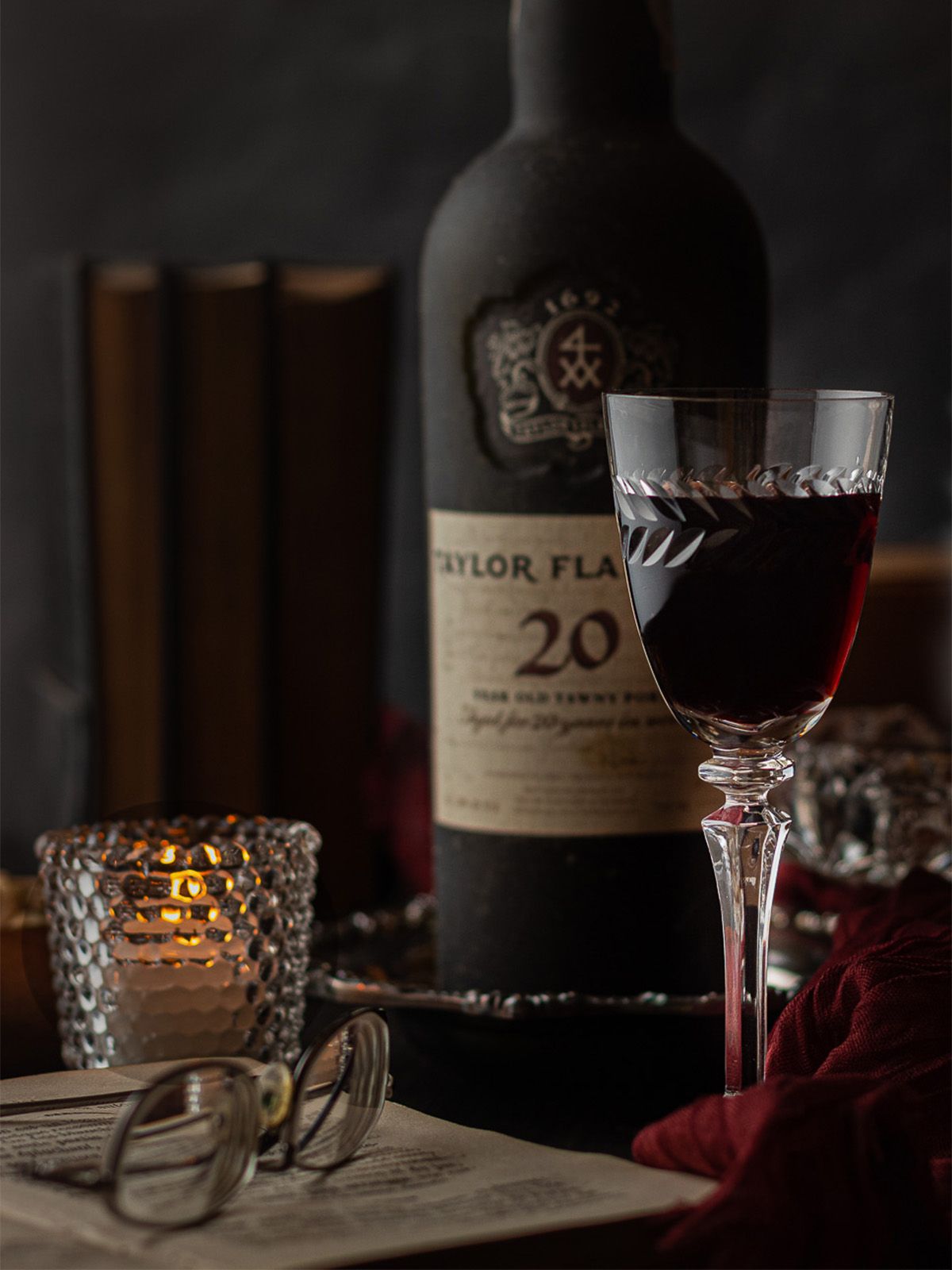 Dark and moody photograph of a glass of port wine in an evening setting