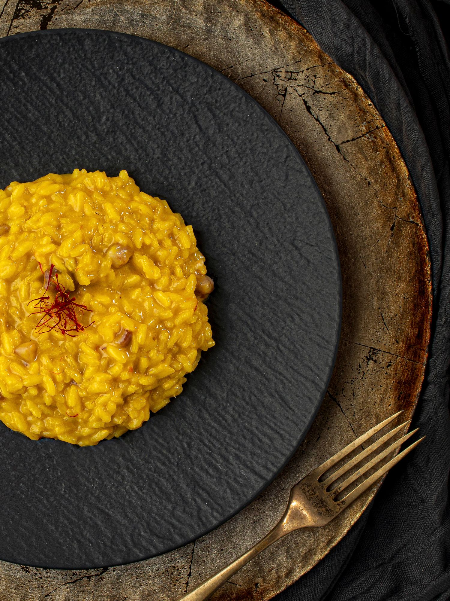 Risotto Milanese with saffron on a black plate, shot from overhead