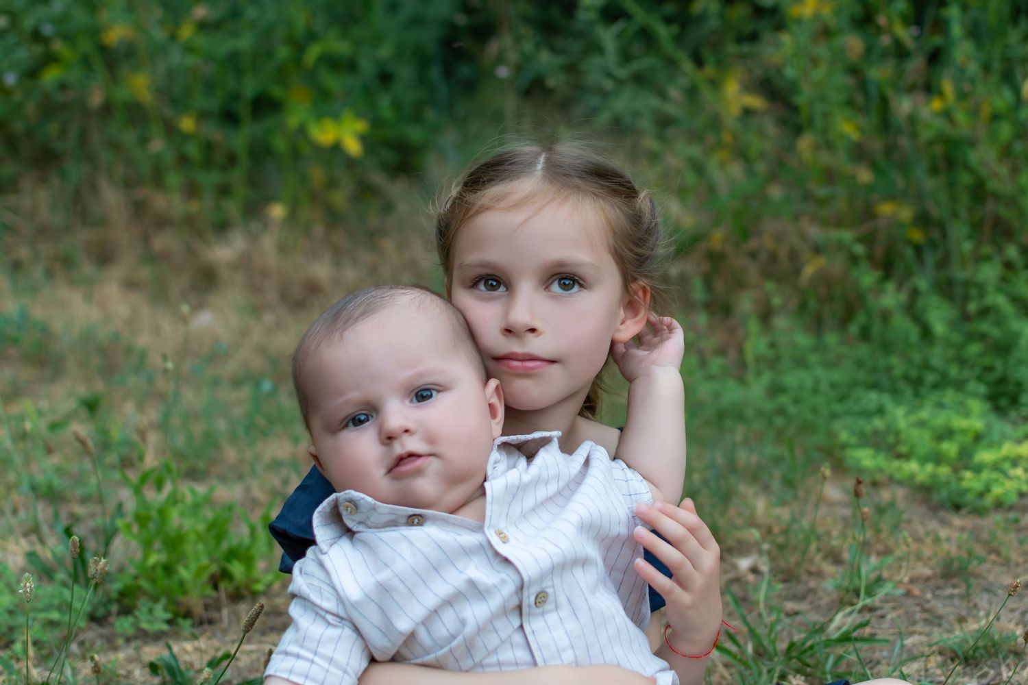 Frère et sœur en extérieur, bébé dans les bras de sa grande sœur, Vaucluse