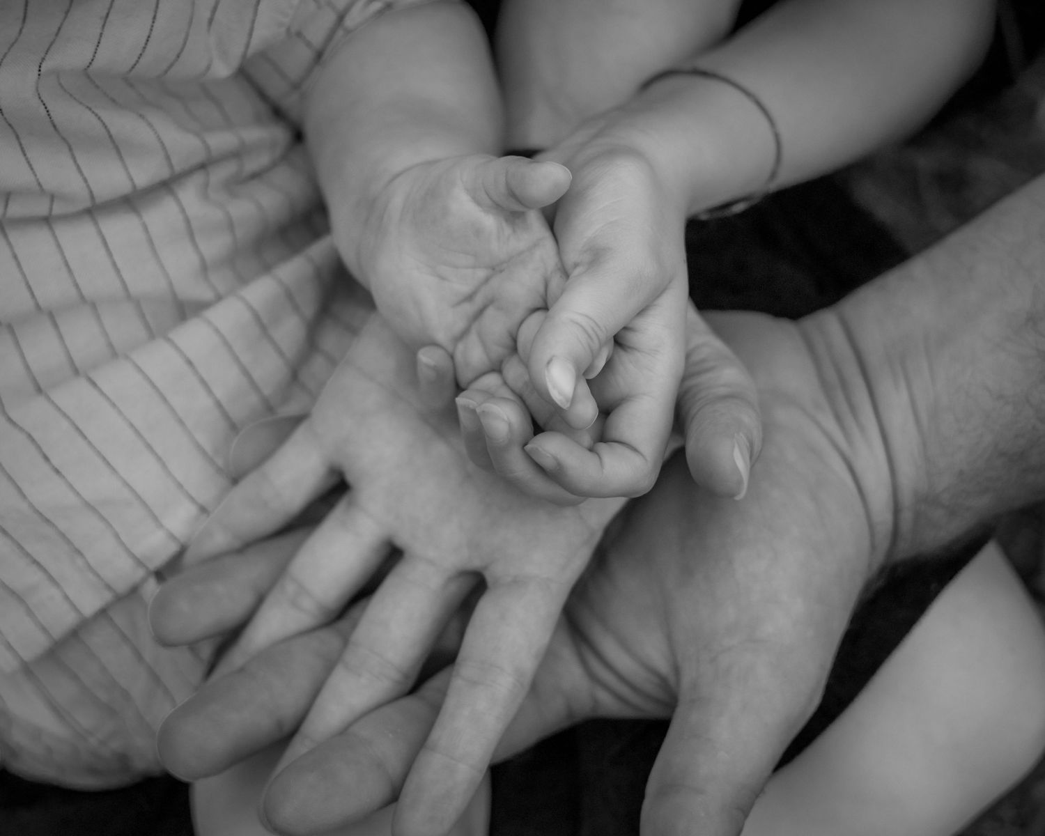 Photo en noir et blanc de mains de famille réunies, symbole de complicité