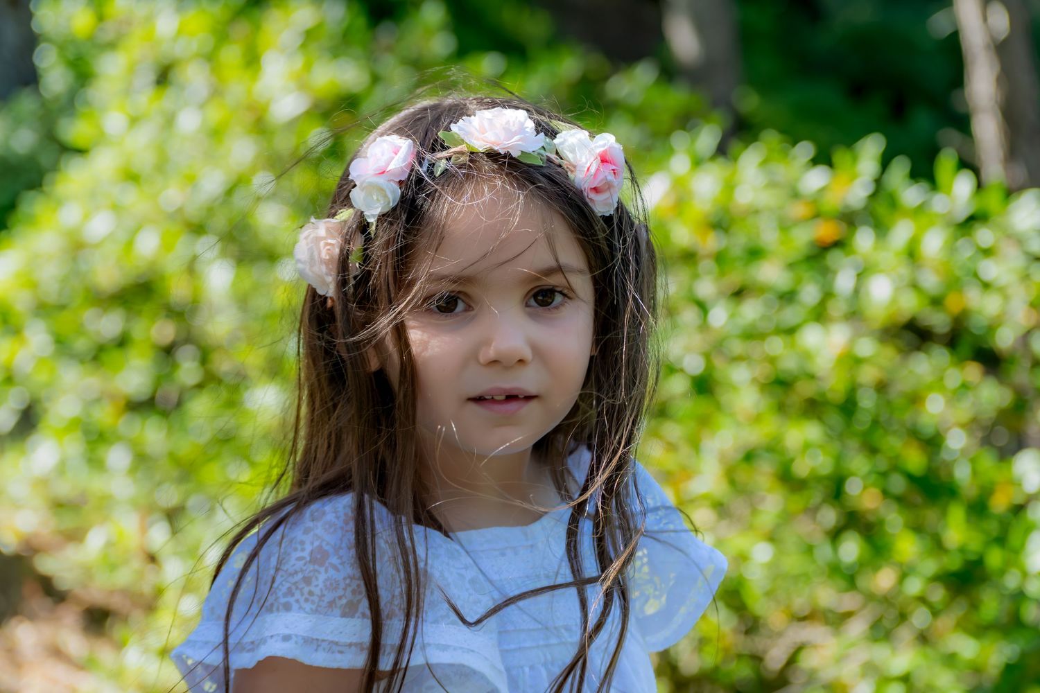 Petite fille avec couronne de fleurs en extérieur, portrait naturel