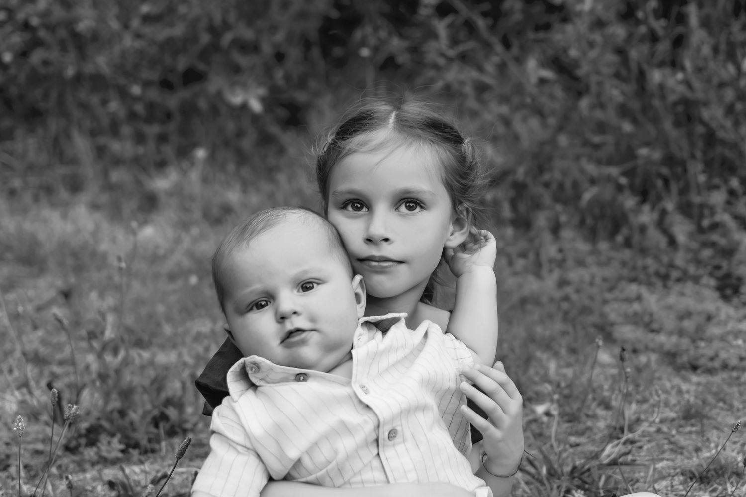Photo de famille en noir et blanc, bébé et grande sœur, complicité fraternelle