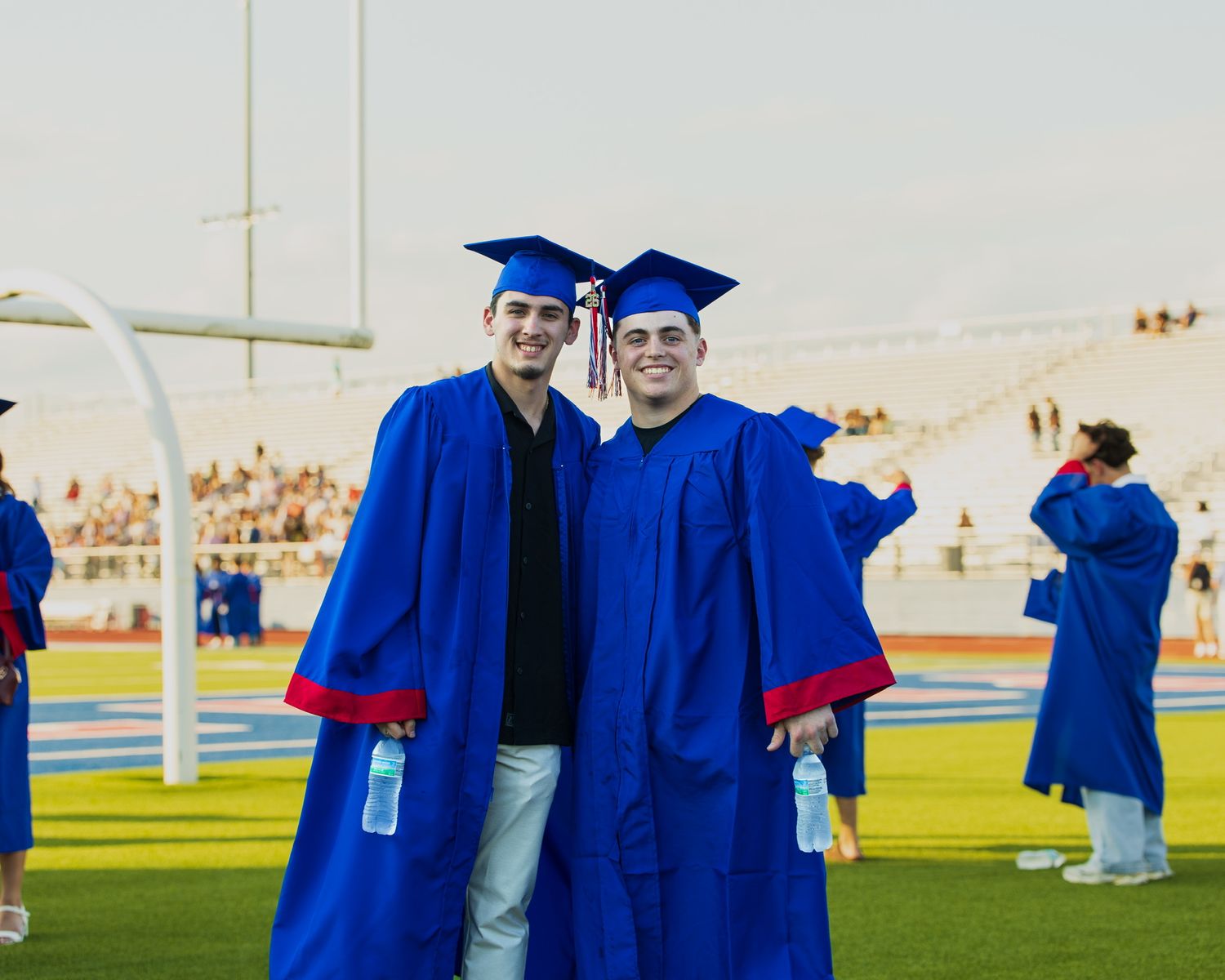 two students in cap and gown smiling at the camera