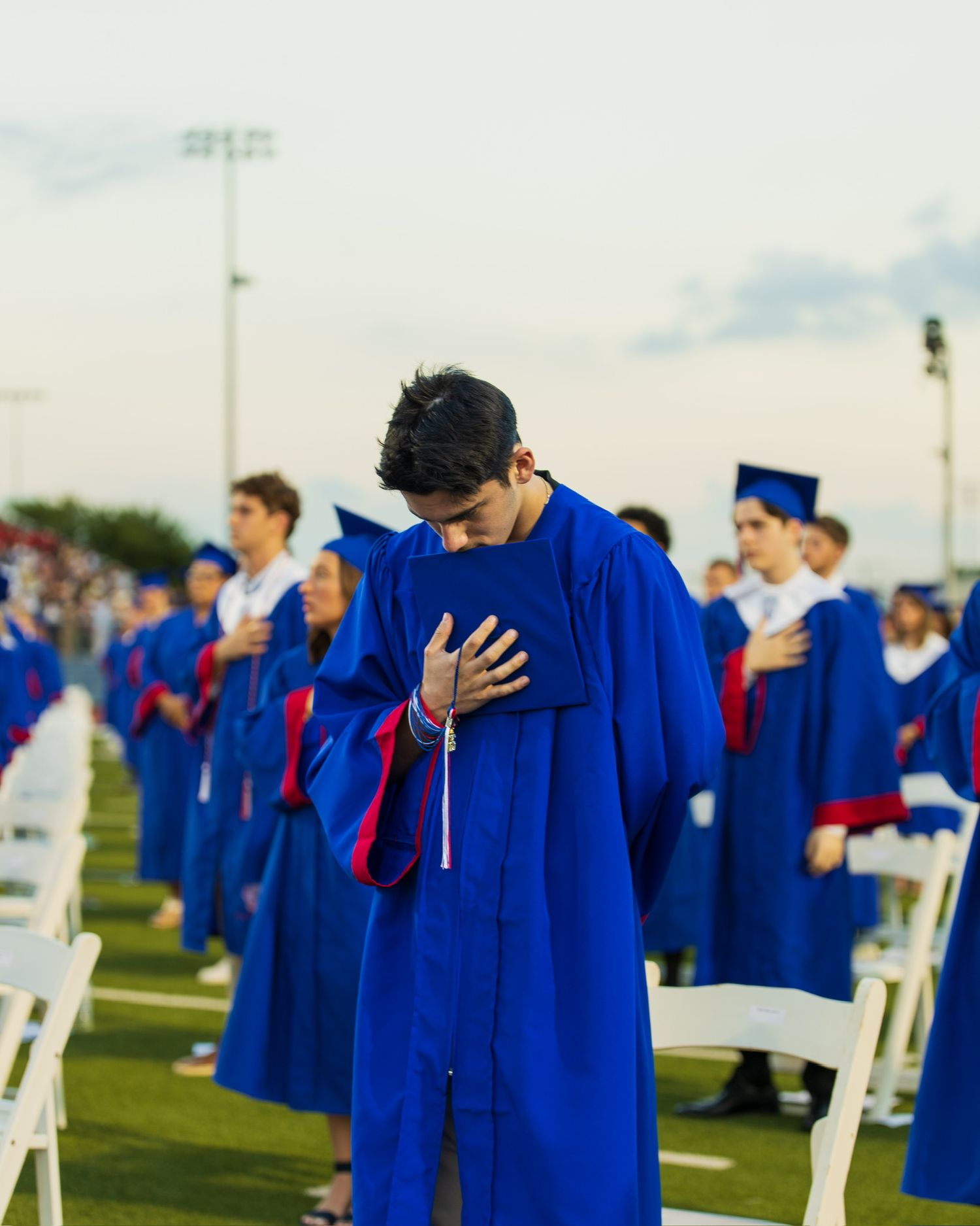 student in cap bowing their head in prayer