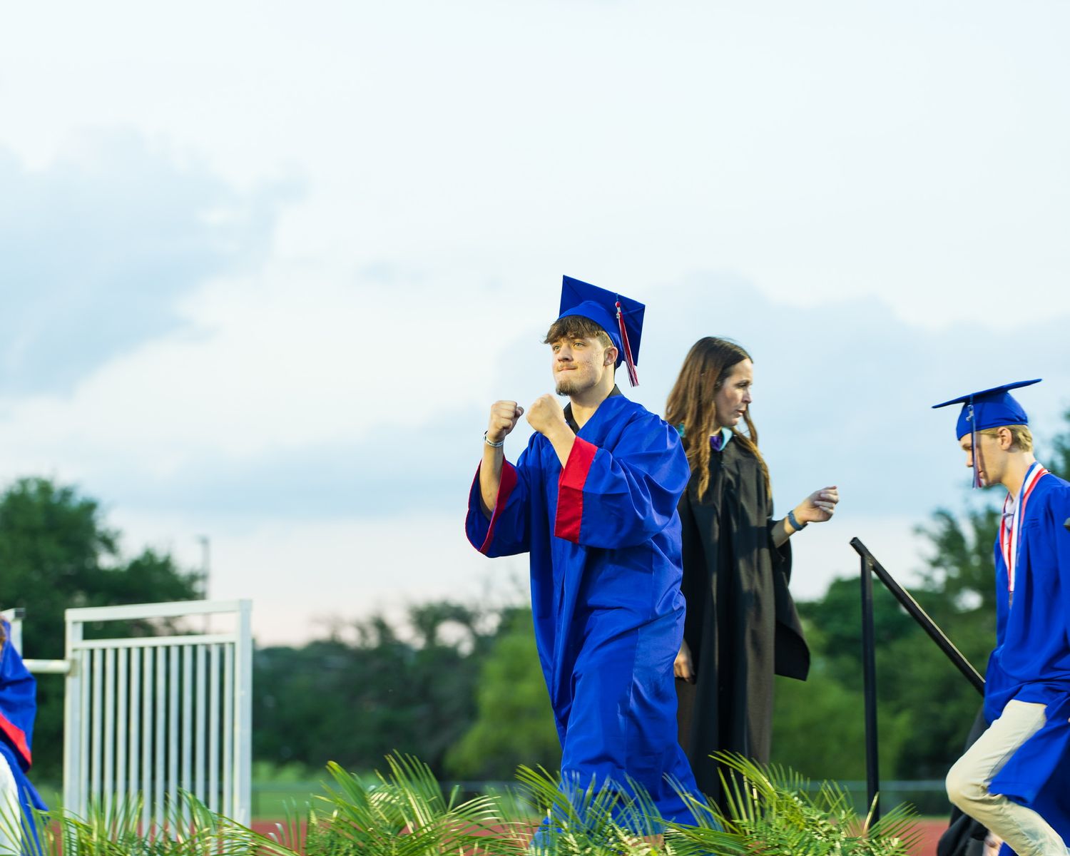 student in cap and gown walking up to the stage at graduation