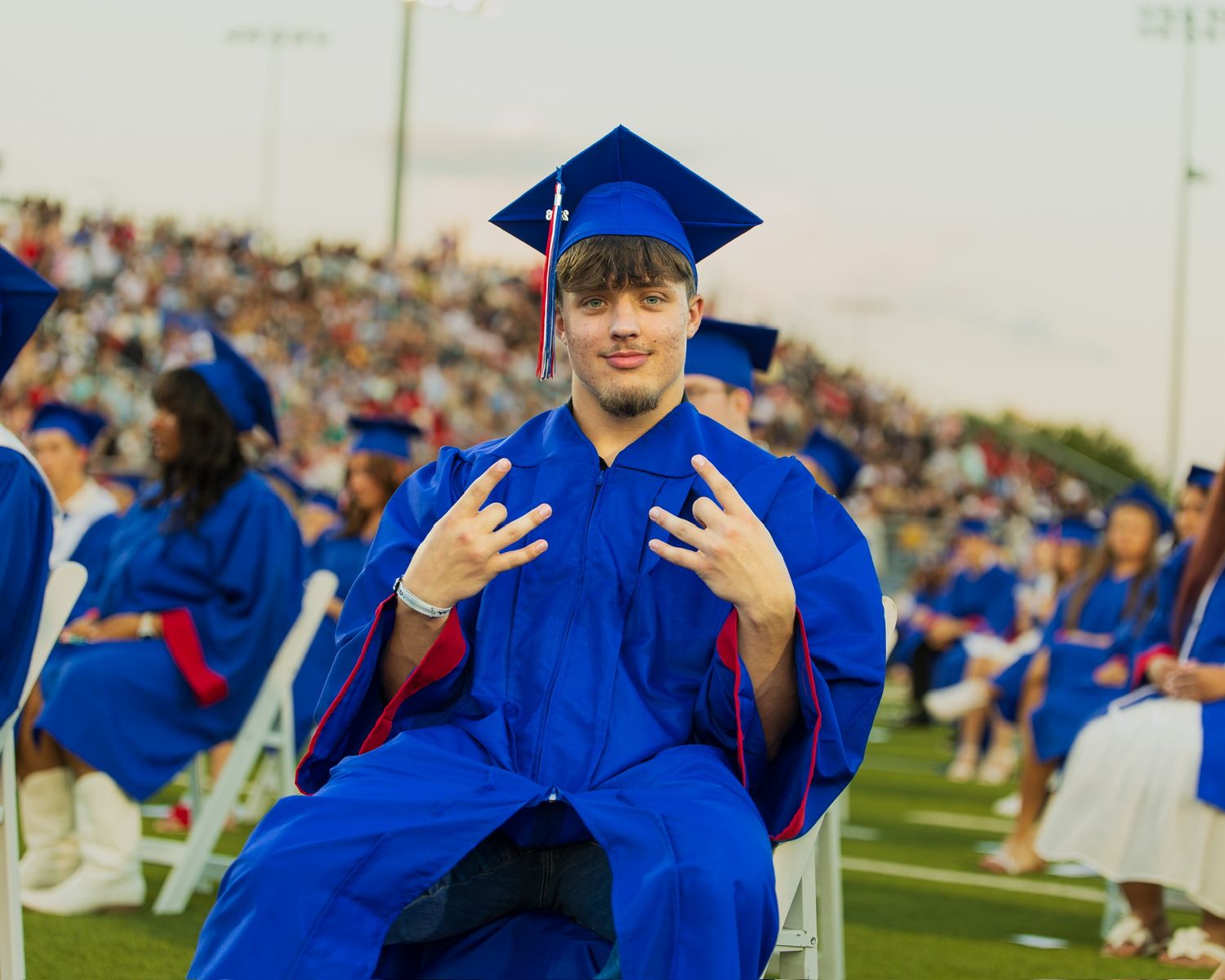 student in cap and gown sitting smiling at the camera