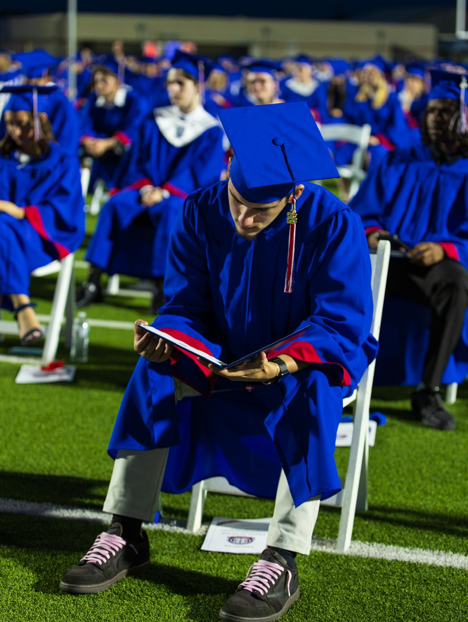 student in cap and gown reading their diploma