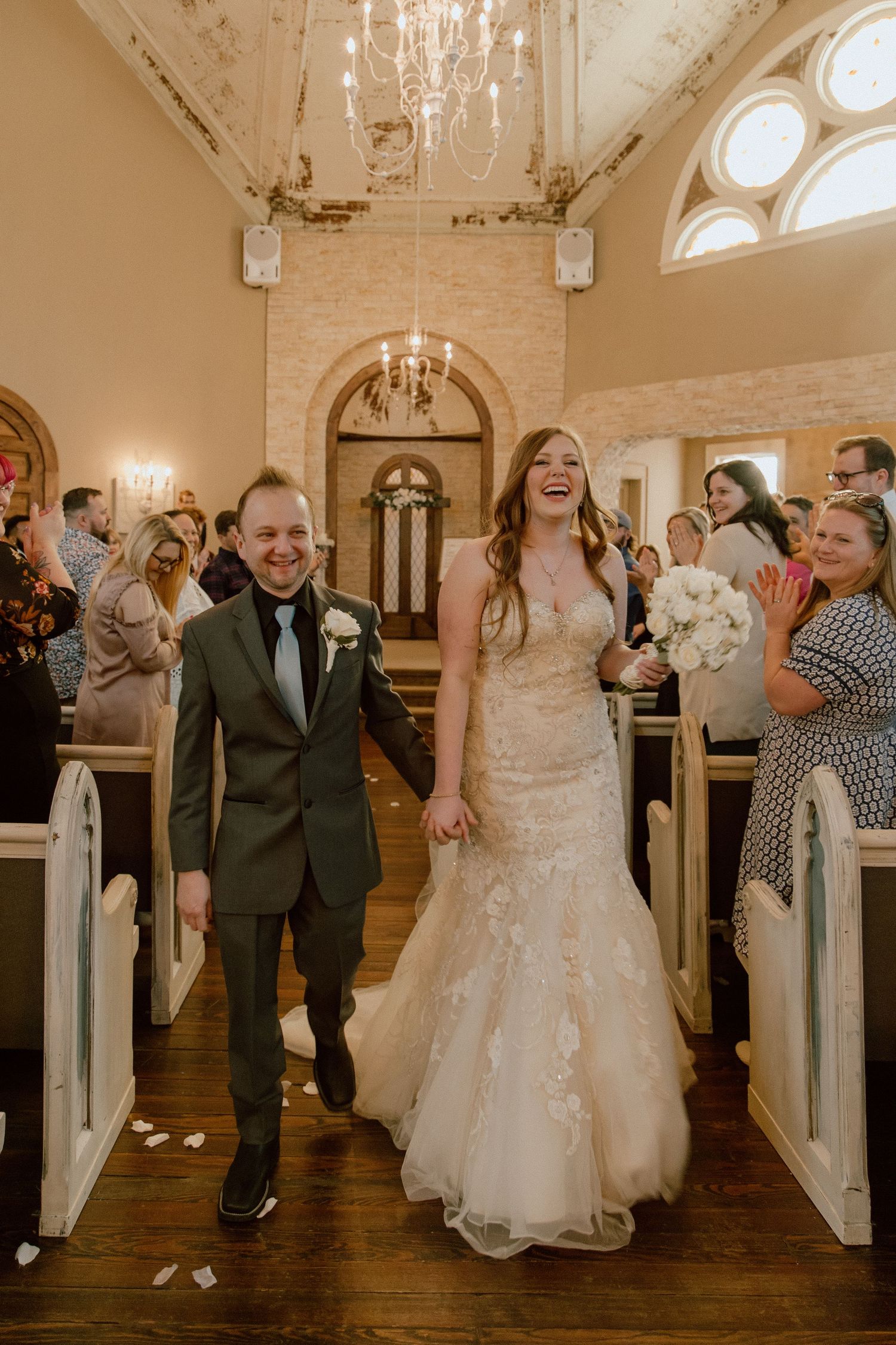 Newlyweds walk joyfully down the aisle of a beautiful chapel after their wedding.