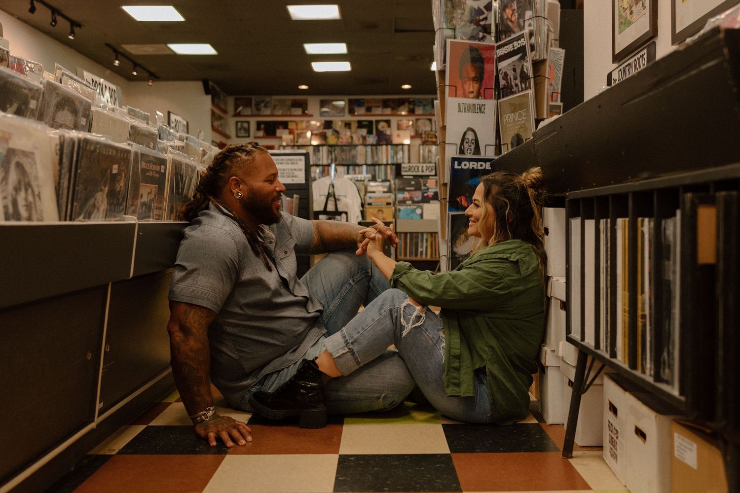 Couple sitting on floor of vinyl record store, laughing and sharing music together.