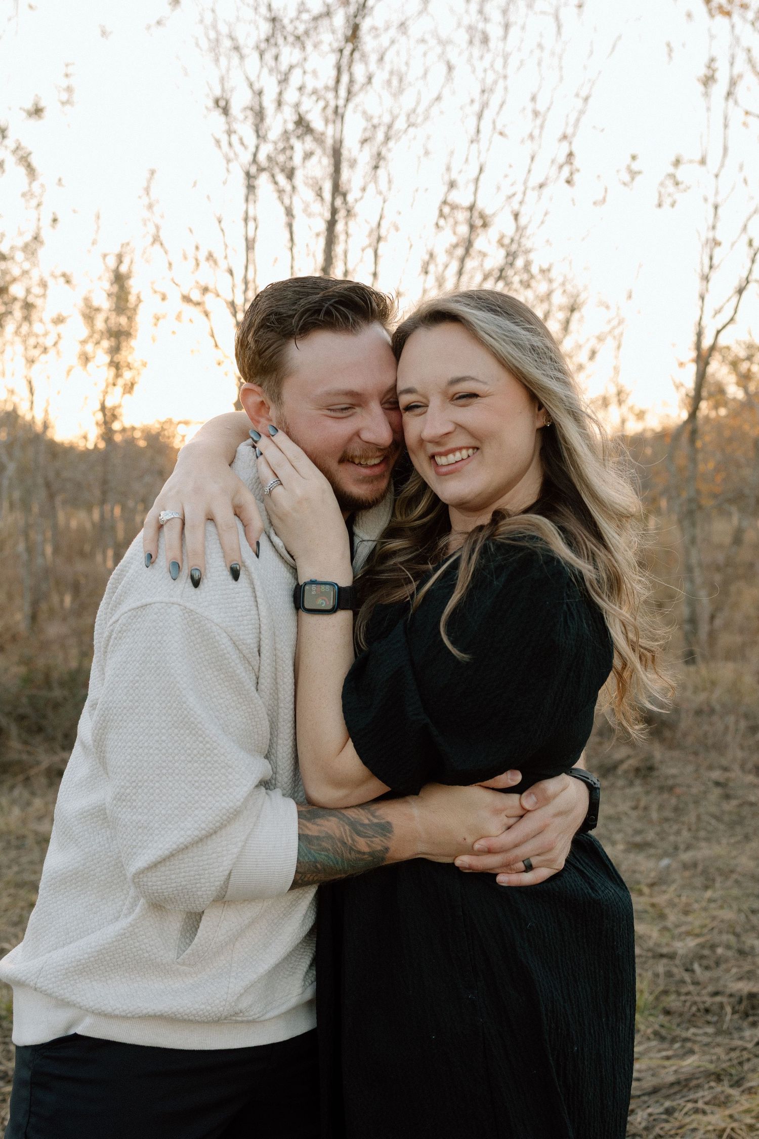 Happy couple shares a tender embrace during a warm sunset engagement shoot outdoors.