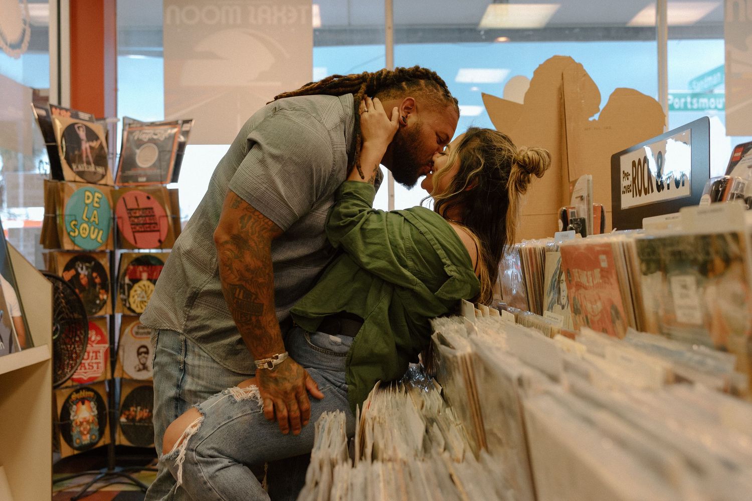 Couple sharing a spontaneous kiss while browsing vinyl records in a colorful music store.