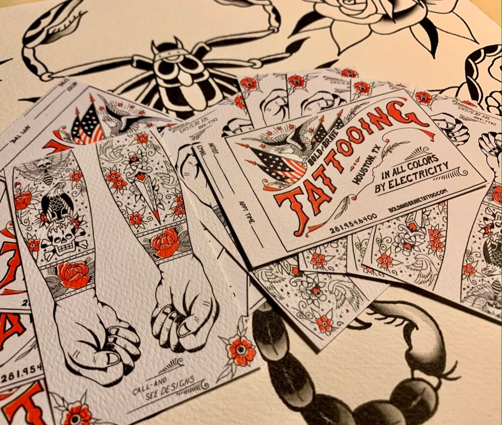 Vintage-style tattooing flash cards with bold black ink designs scattered on a white surface.