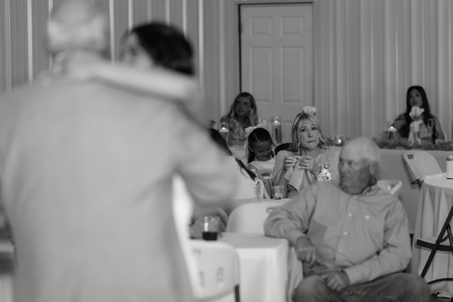 Wedding reception guests seated at tables watching a heartfelt toast speech.