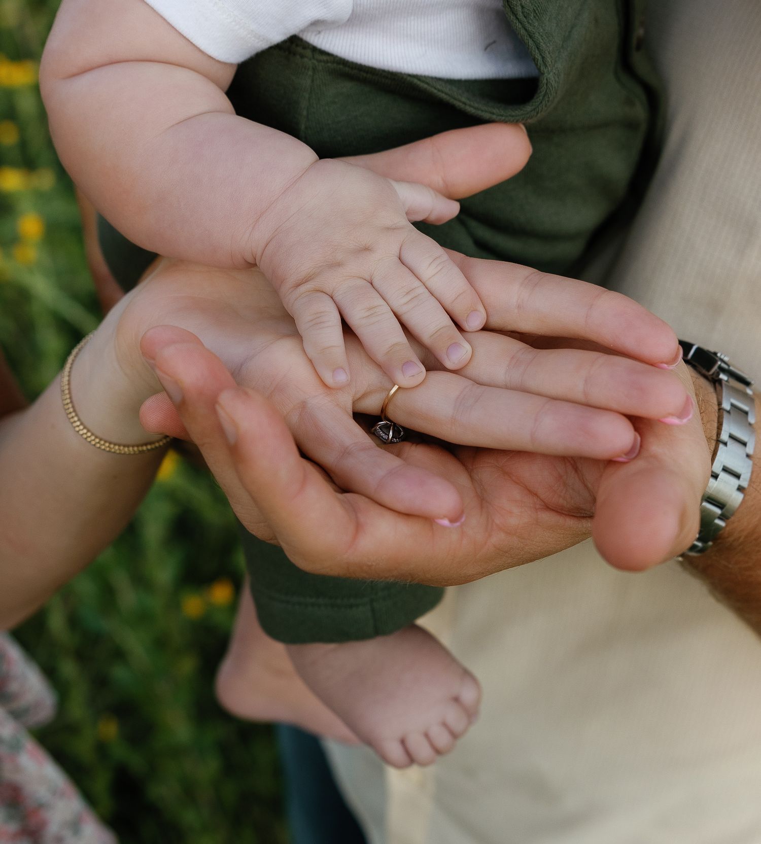 Close-up of a baby's tiny hand resting on parents' hands, symbolizing new family bond.