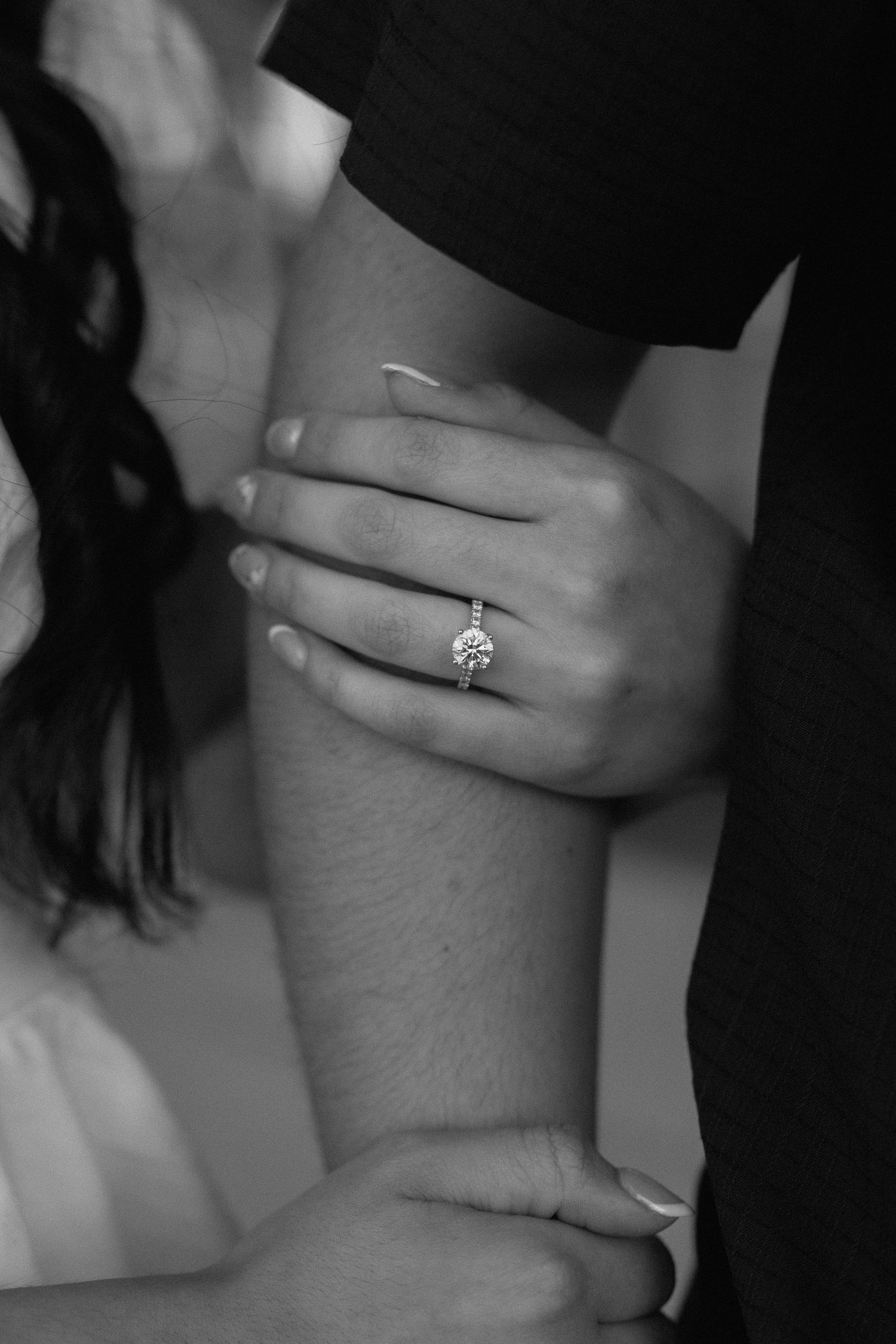 Close-up black and white photo of a woman's hand showing a stunning solitaire diamond engagement ring.