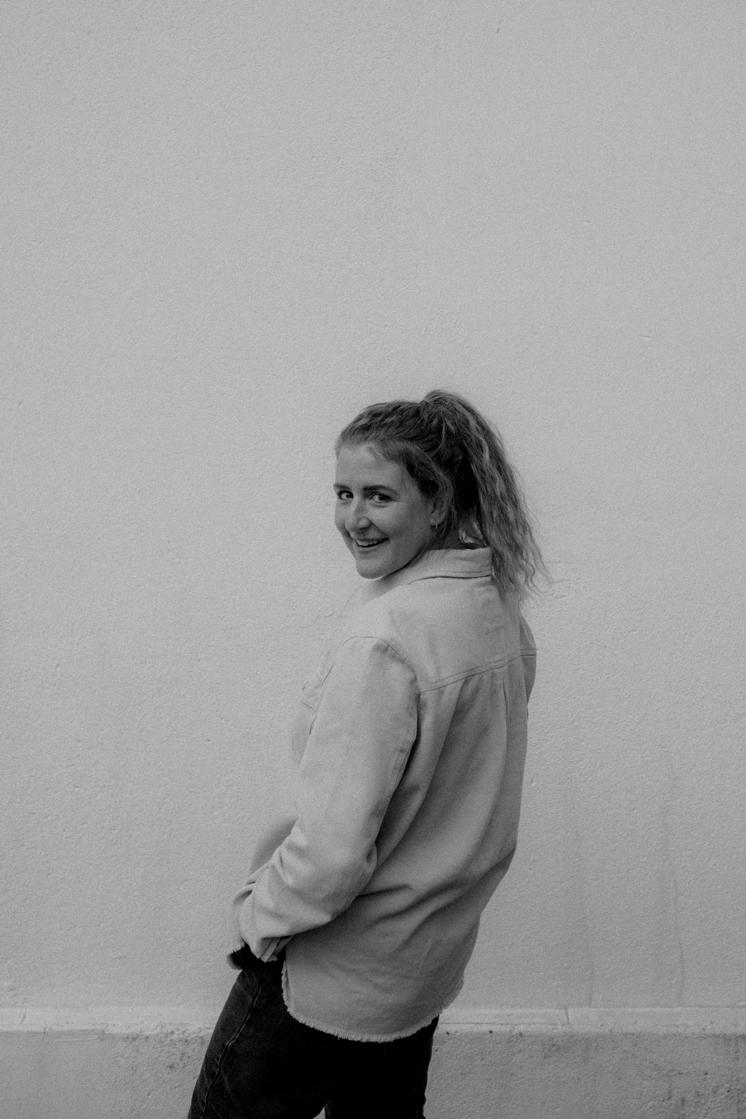 A sequence of black and white photographs shows a person in a light-colored sweater turning around against a plain wall.