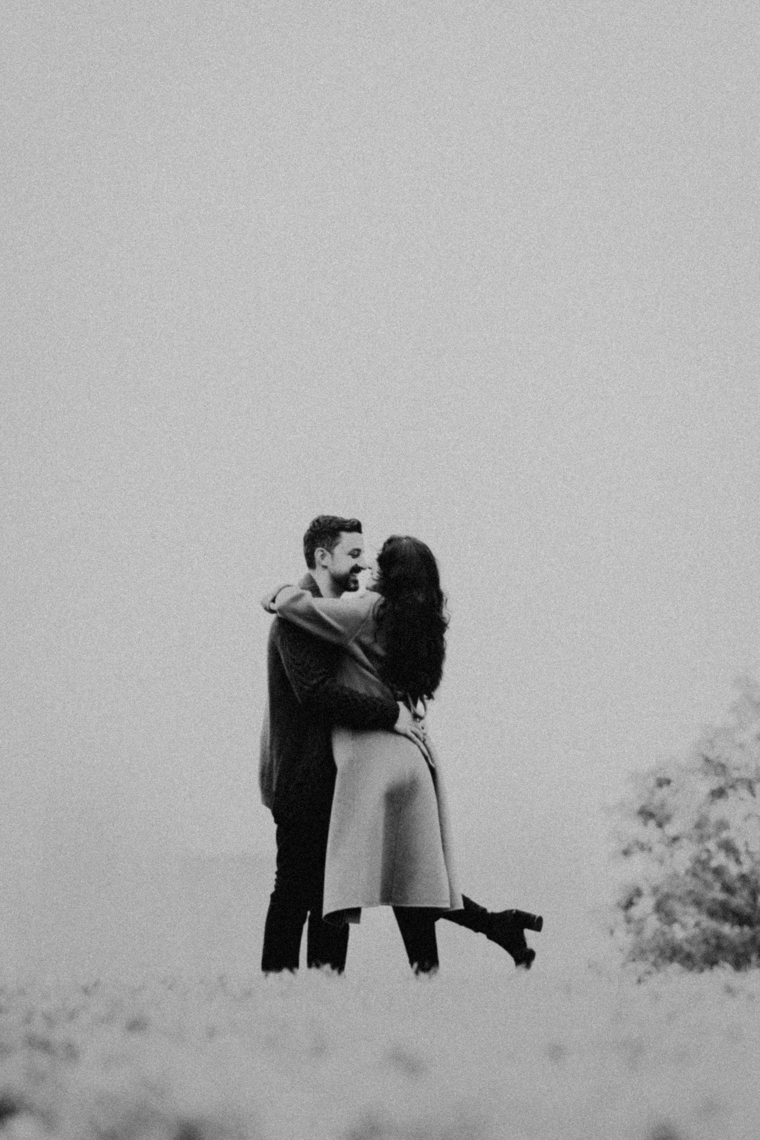 Memory Lane Studios romantic black and white engagement portrait of couple embracing on misty hillside by photographer Tharun Palla