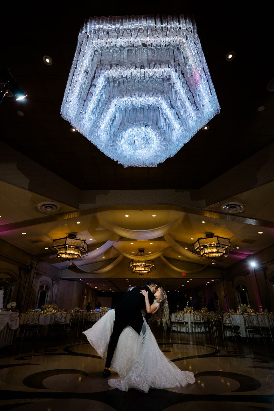 Memory Lane Studios luxury Jewish wedding photography featuring couple dancing beneath grand crystal chandelier at elegant ballroom receptio