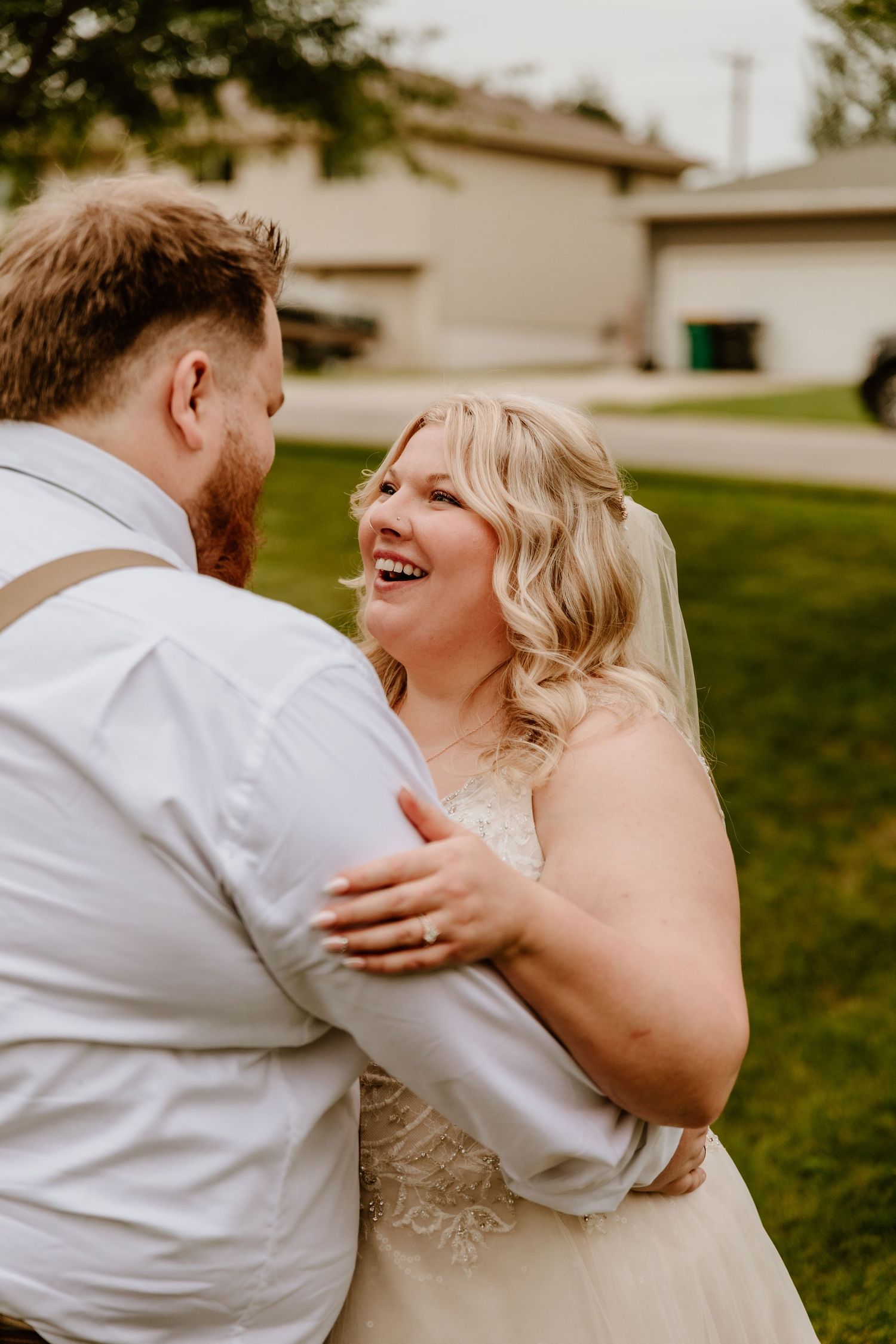 A joyful wedding moment captured outdoors as newlyweds share a candid laugh together on their special day.