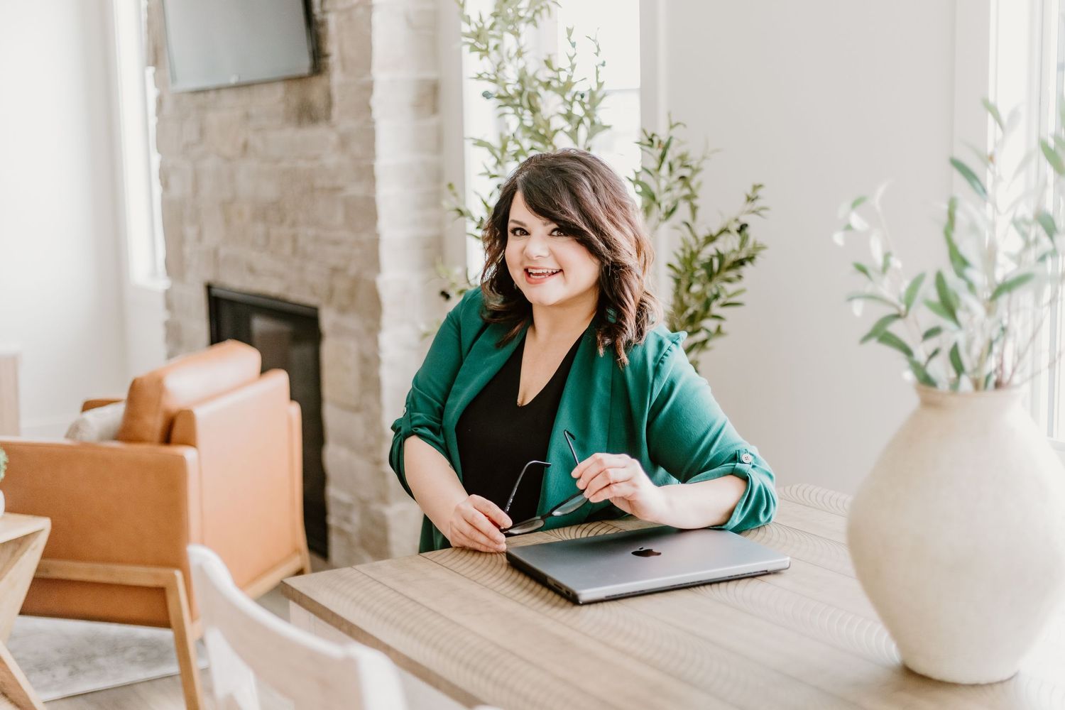 Professional content creator working at a clean white desk with a laptop and modern workspace decor.