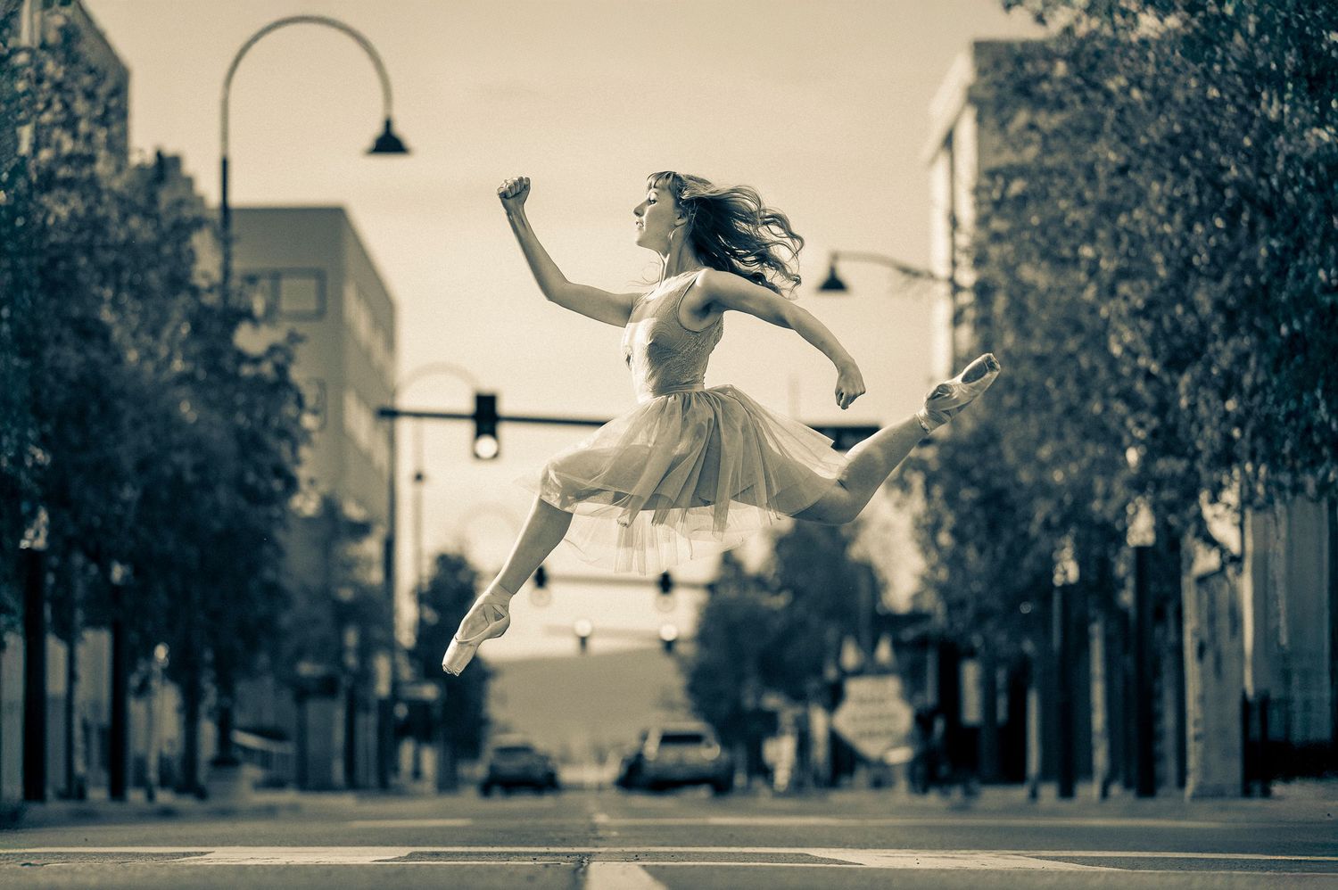 A sepia-toned montage of ballet dancers performing graceful leaps and movements on city streets.