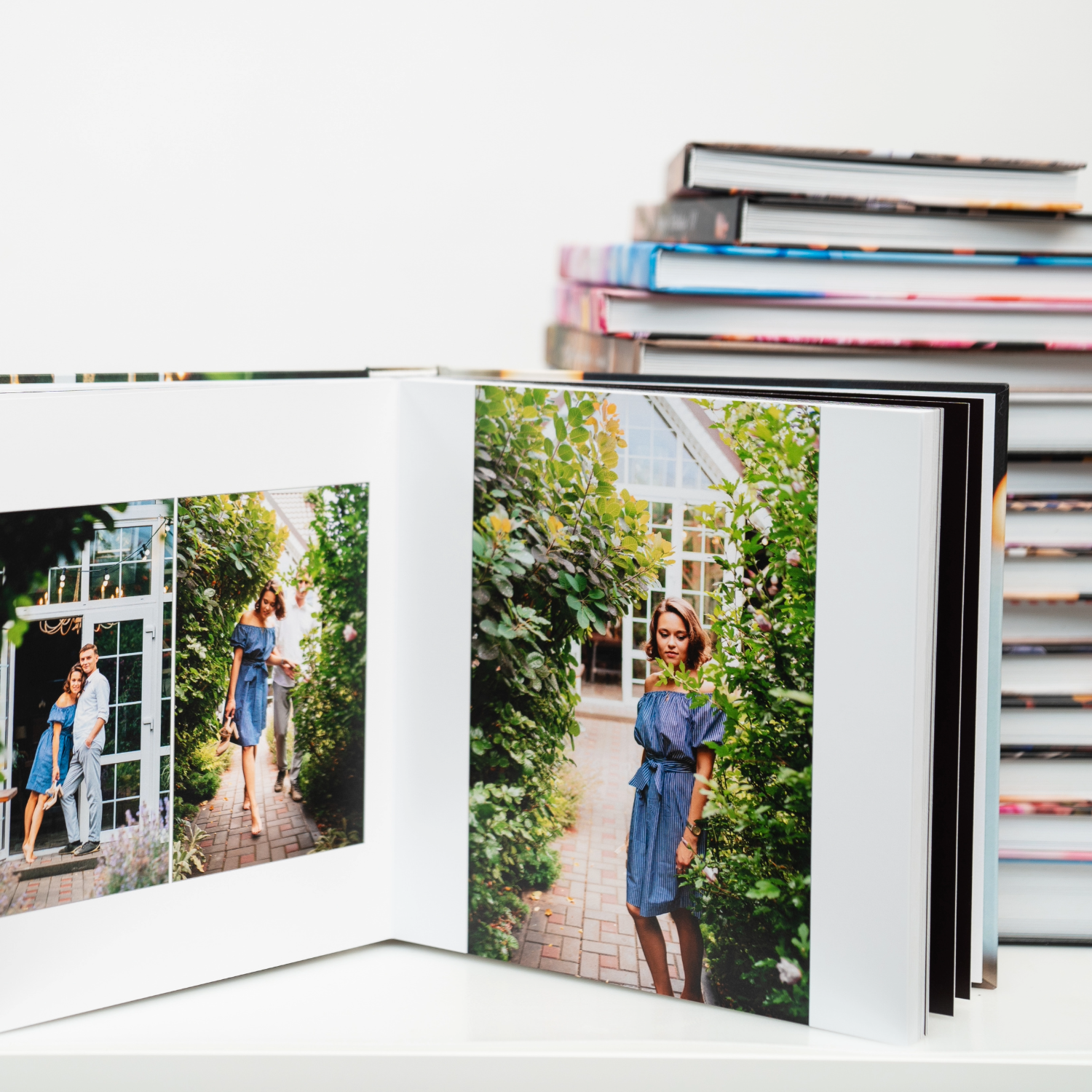 Photo album with printed portraits displayed open on a stack of books and photo albums.