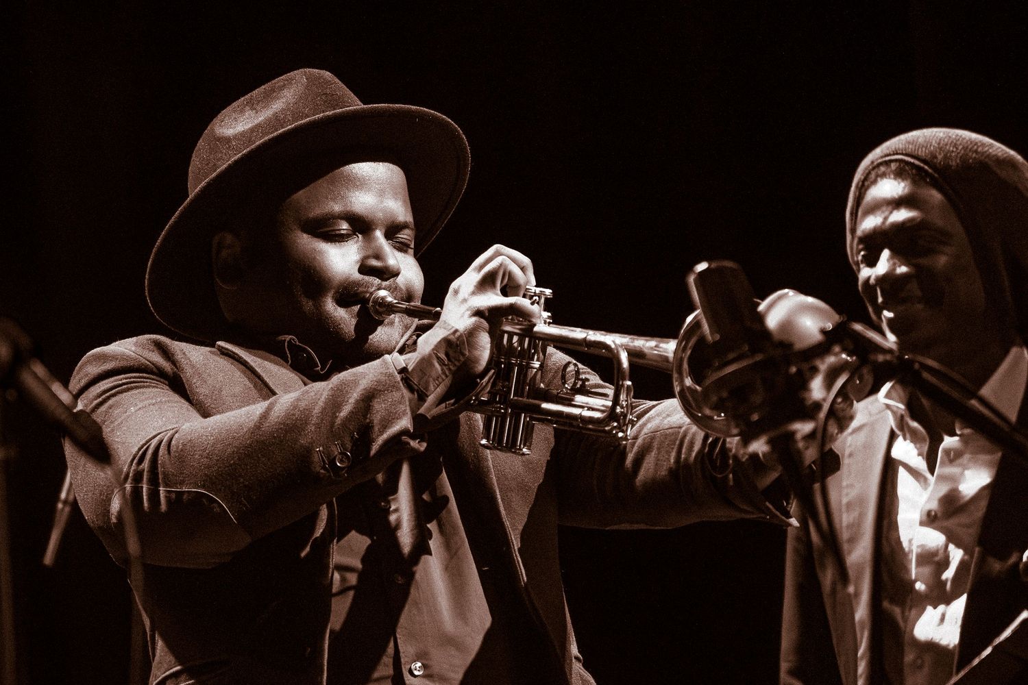 Jazz musicians perform on stage with brass instruments and string bass in dramatic lighting during a live concert.