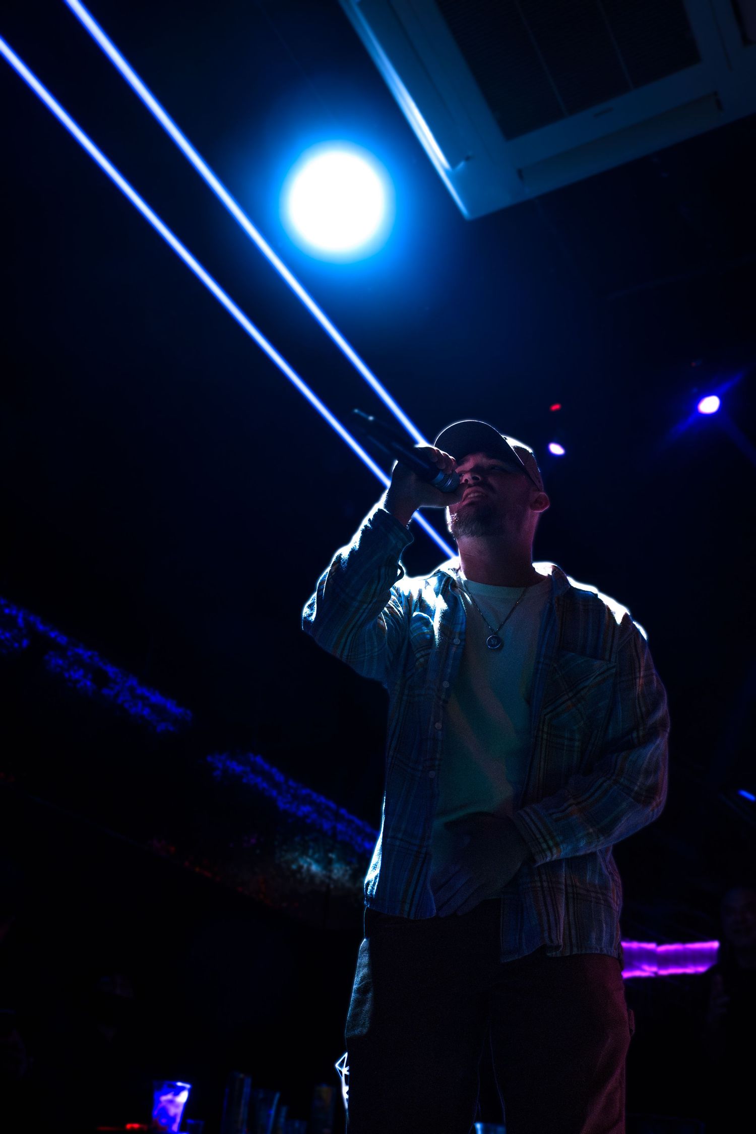 A performer sings on stage under dramatic blue lighting at a nightclub.