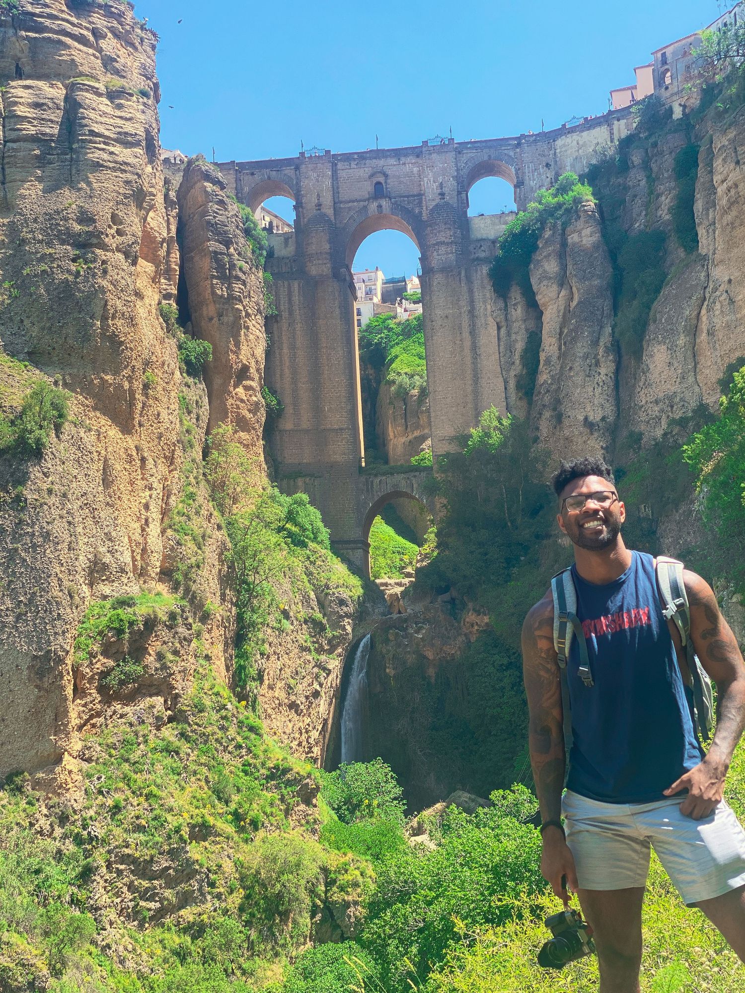Spectacular view of Puente Nuevo bridge spanning deep gorge in Ronda, Spain with rugged cliffs and lush vegetation.