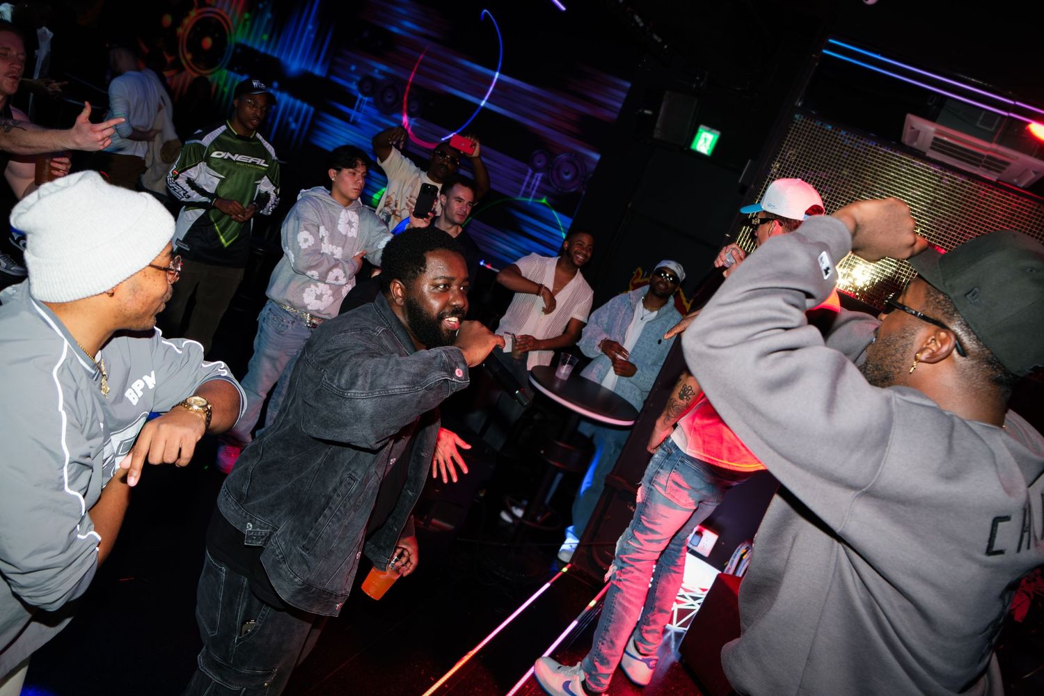 Crowd enjoying a performance in a nightclub with blue lighting and lasers.