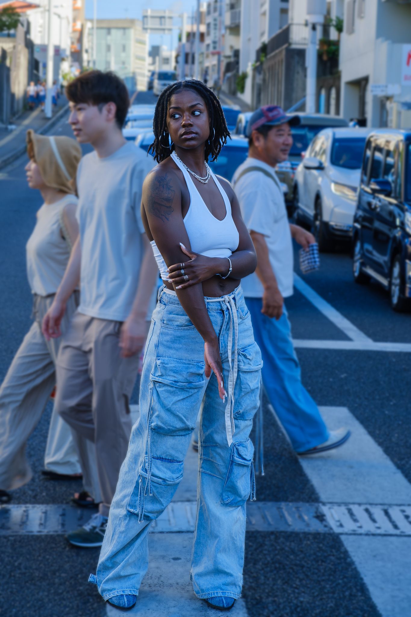 Street fashion portrait with ripped jeans and white tank top in urban setting.