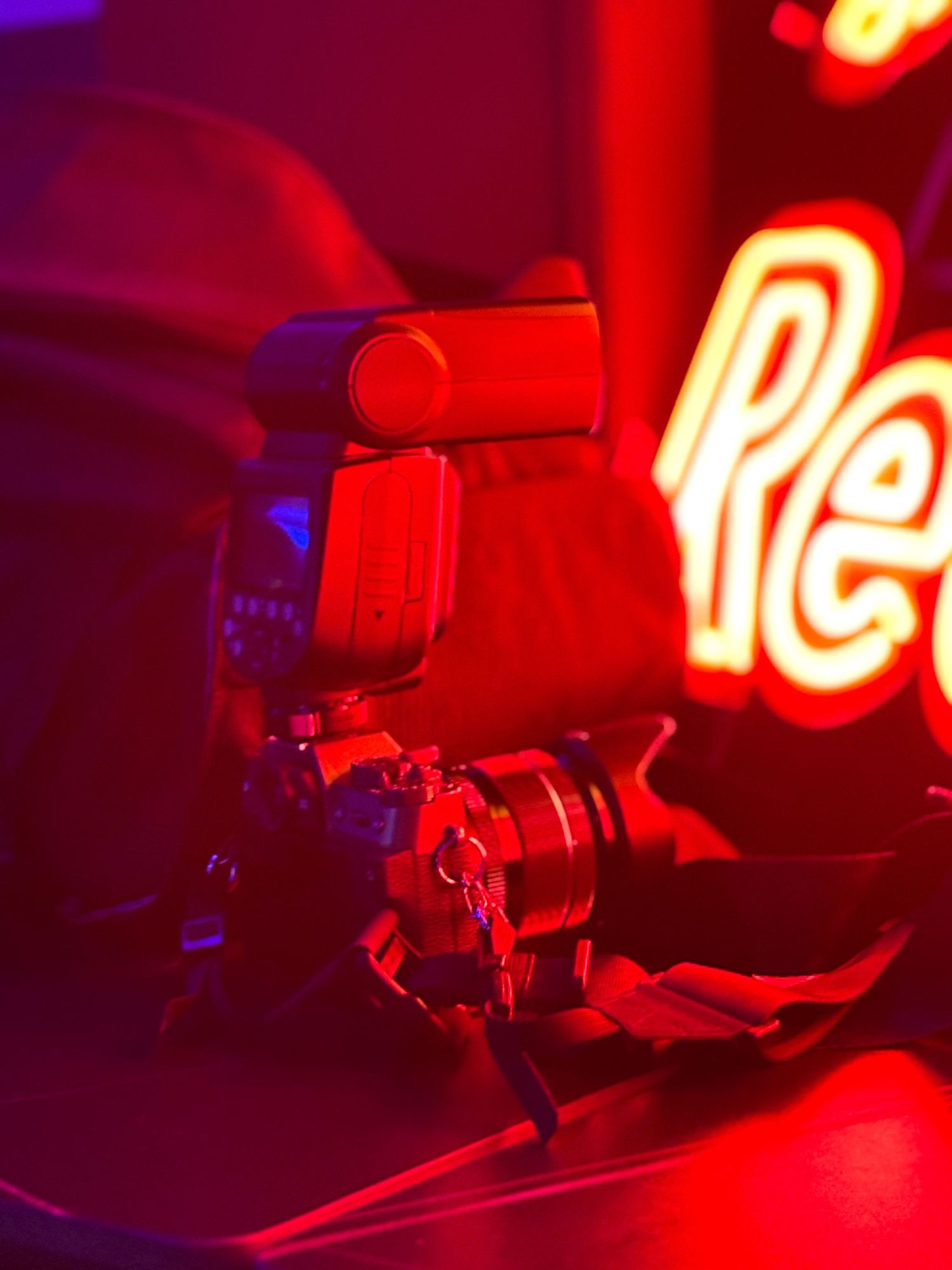 Professional camera setup illuminated by vibrant red neon lighting in a dark studio atmosphere.