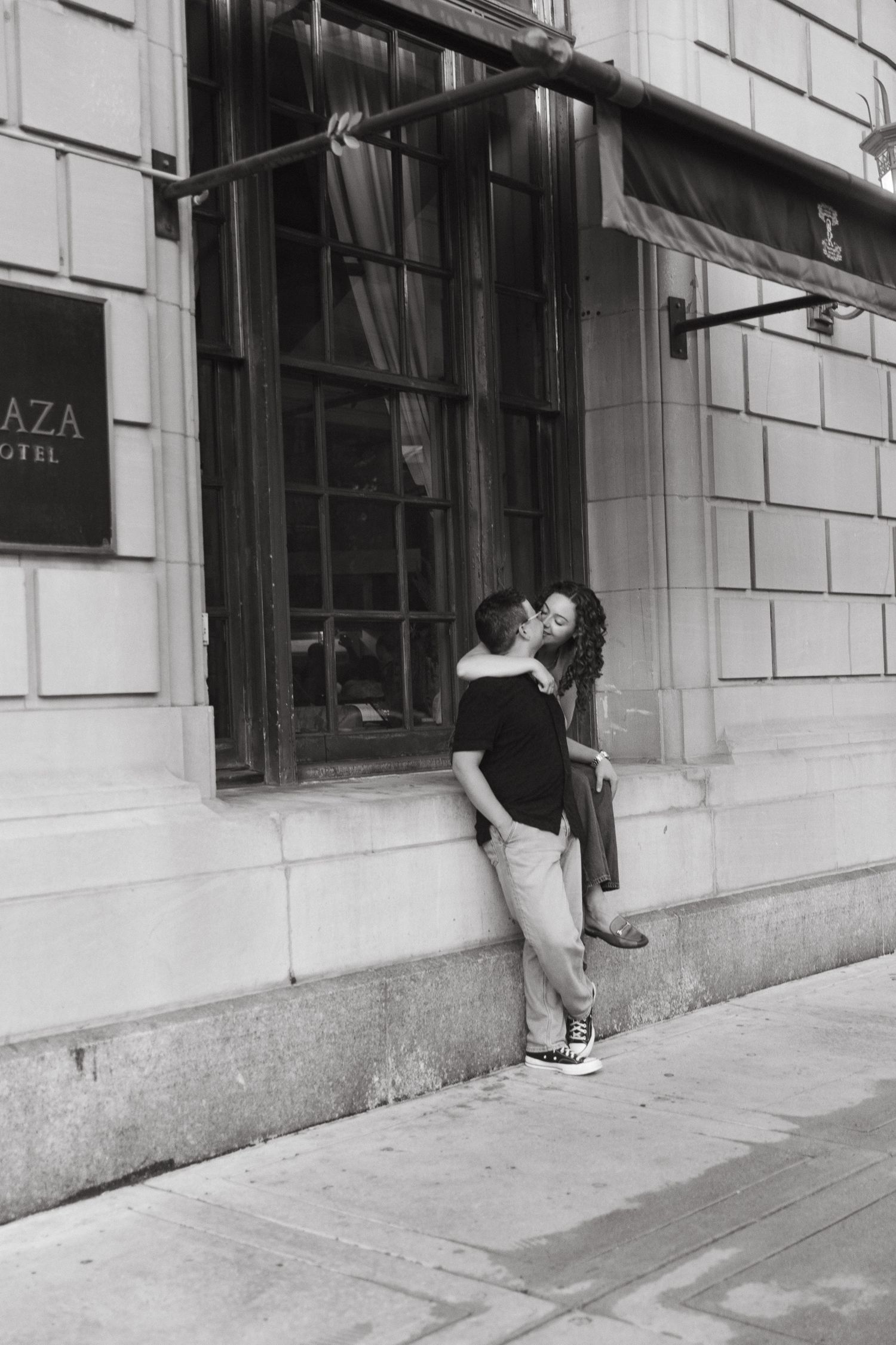 Series of black and white photos showing a couple being playful along a building wall.