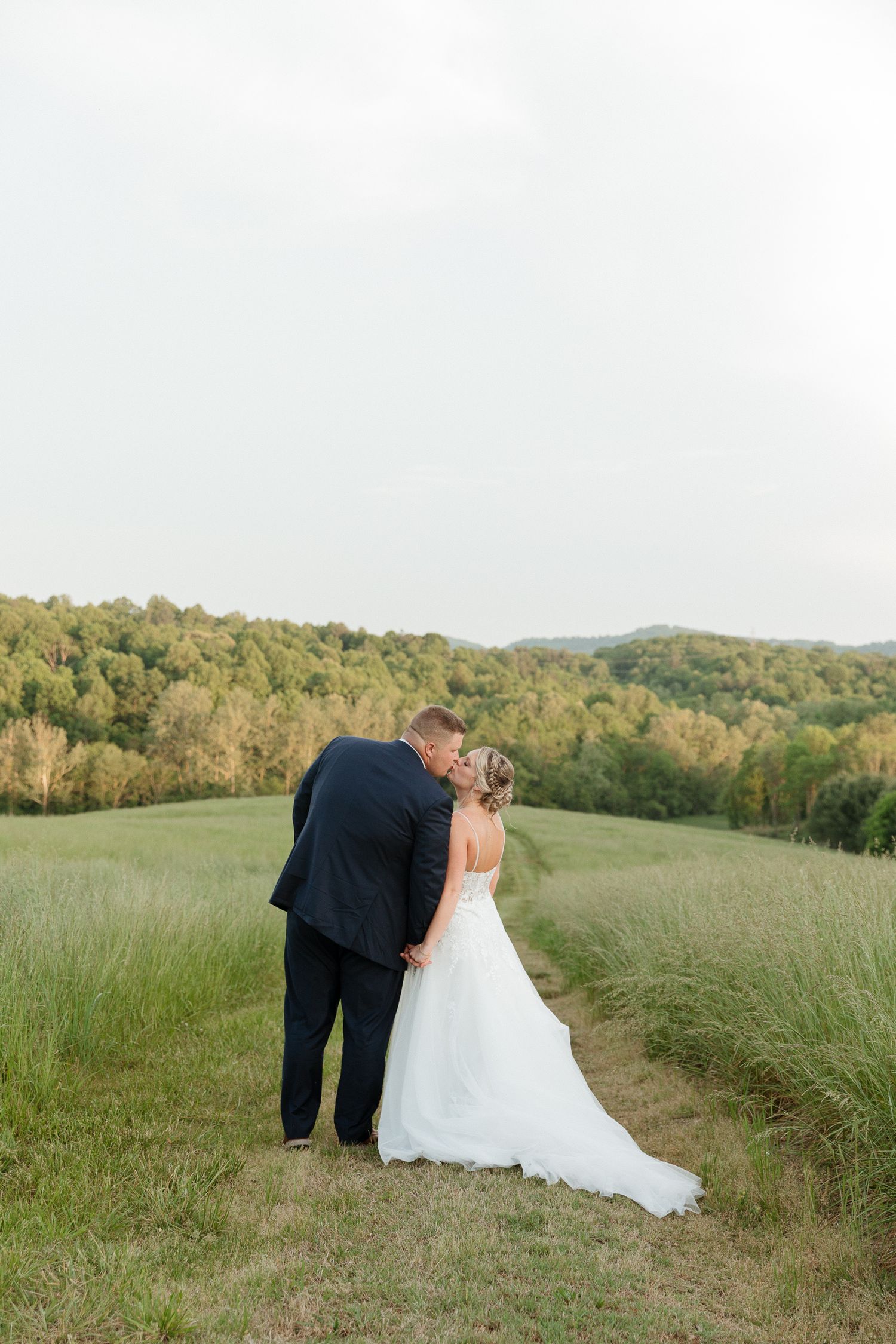 A romantic moment between newlyweds on a hilltop overlooking rolling countryside.