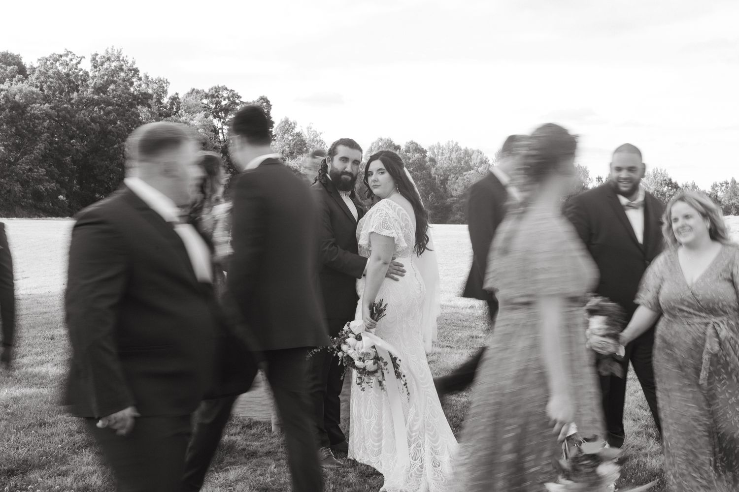 A group of wedding guests celebrate outdoors in black and white photography.