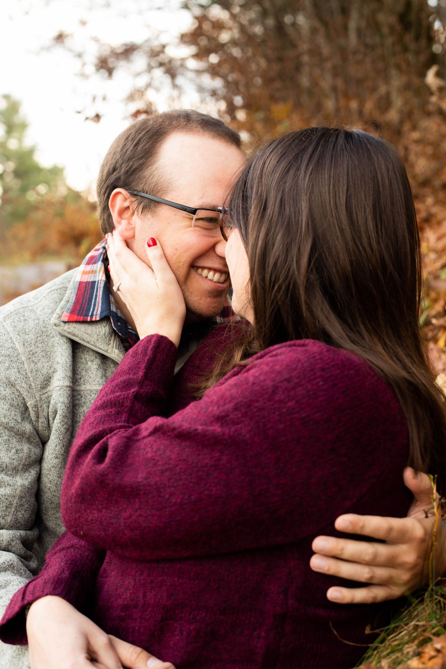 Cozy autumn engagement photos with couple in burgundy sweater.