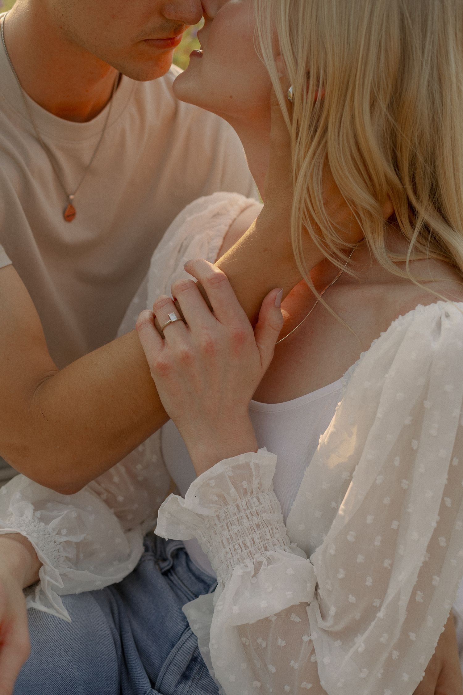 Romantic close-up of couple in white and casual attire during golden hour.