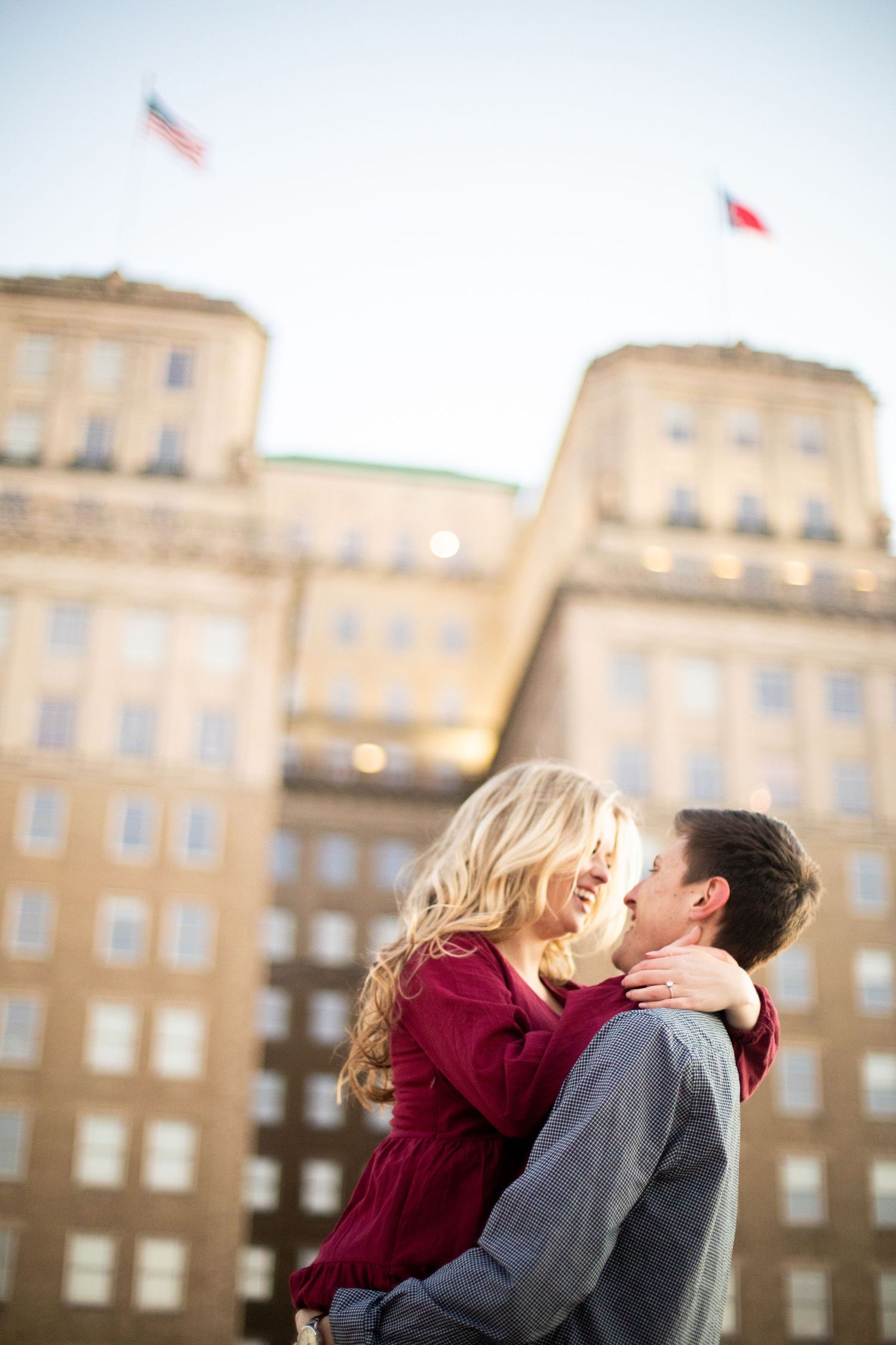 A romantic embrace in front of a historic building with flags waving above.