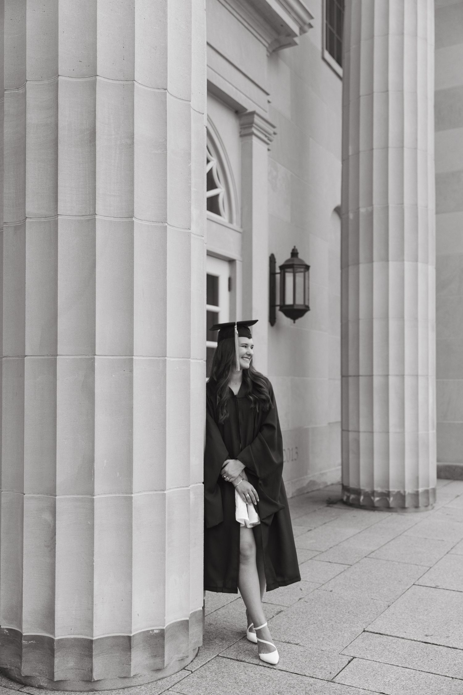 Architectural detail of white classical columns with person posing between them.