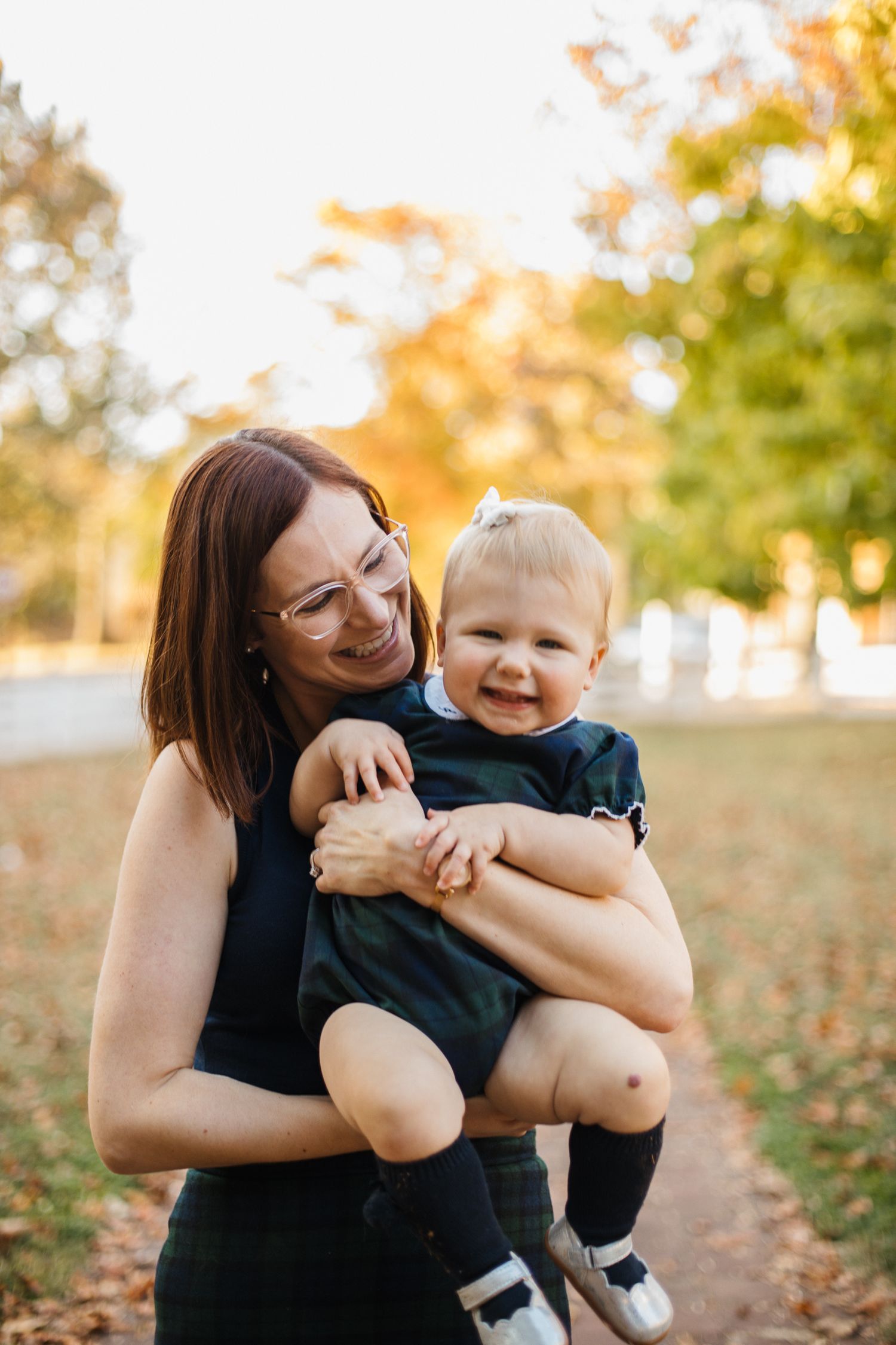Parent and baby sharing joyful moments together in autumn sunlight.