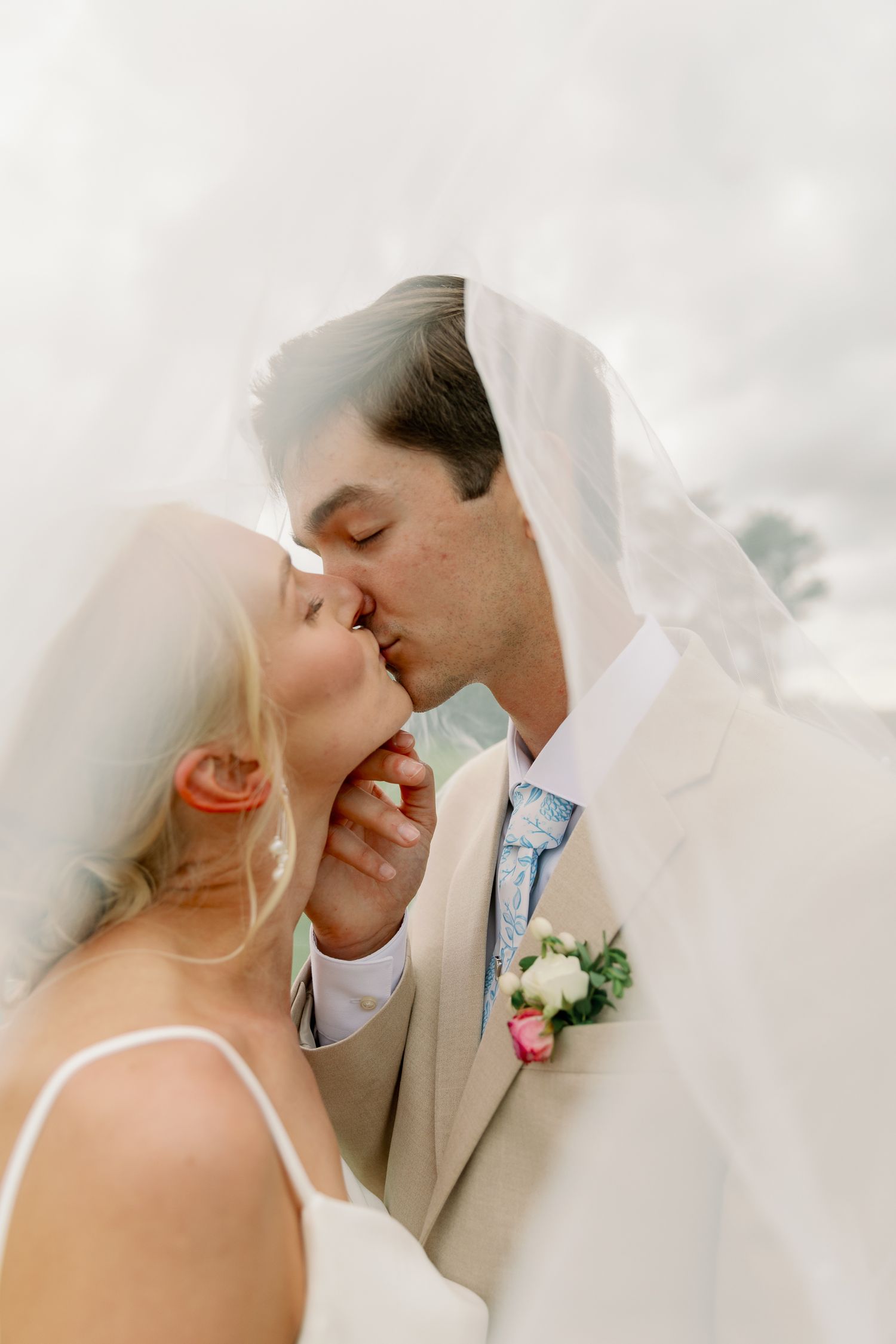 An intimate wedding portrait captured under a flowing white veil.