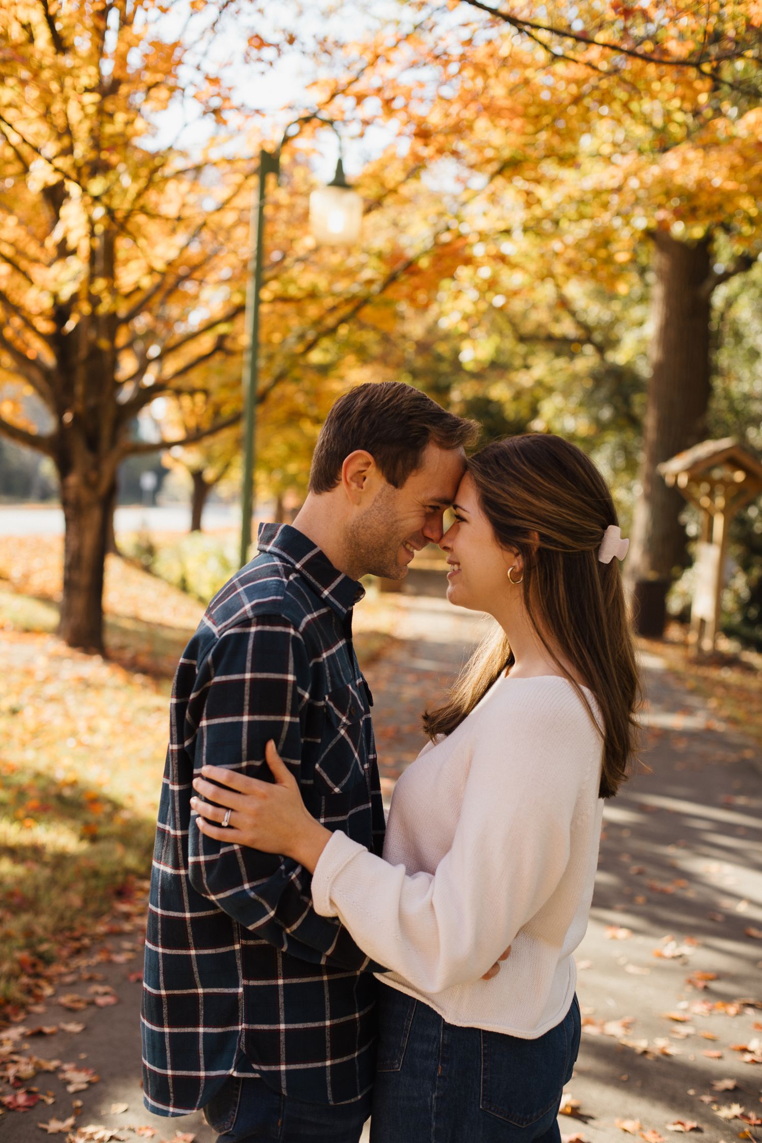 A couple shares an intimate moment under golden fall foliage.