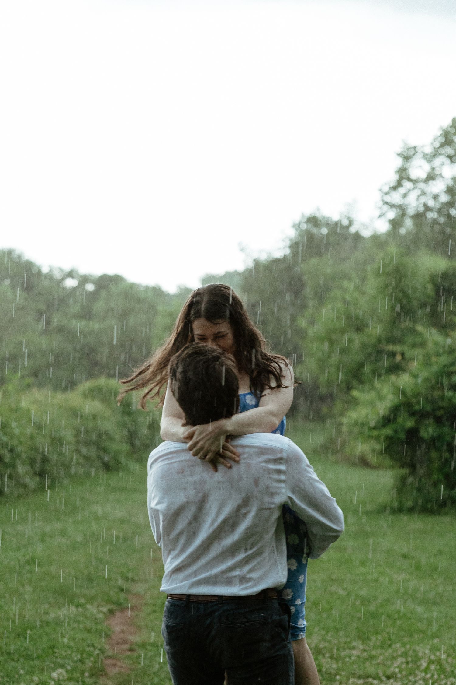 People embracing in a grassy field on an overcast day.