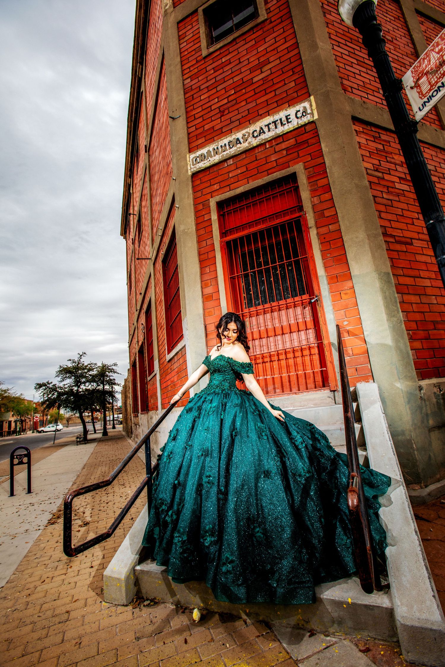 Stylish quinceañera in Union Plaza, posing against historic brick buildings and modern city vibes in downtown El Paso.