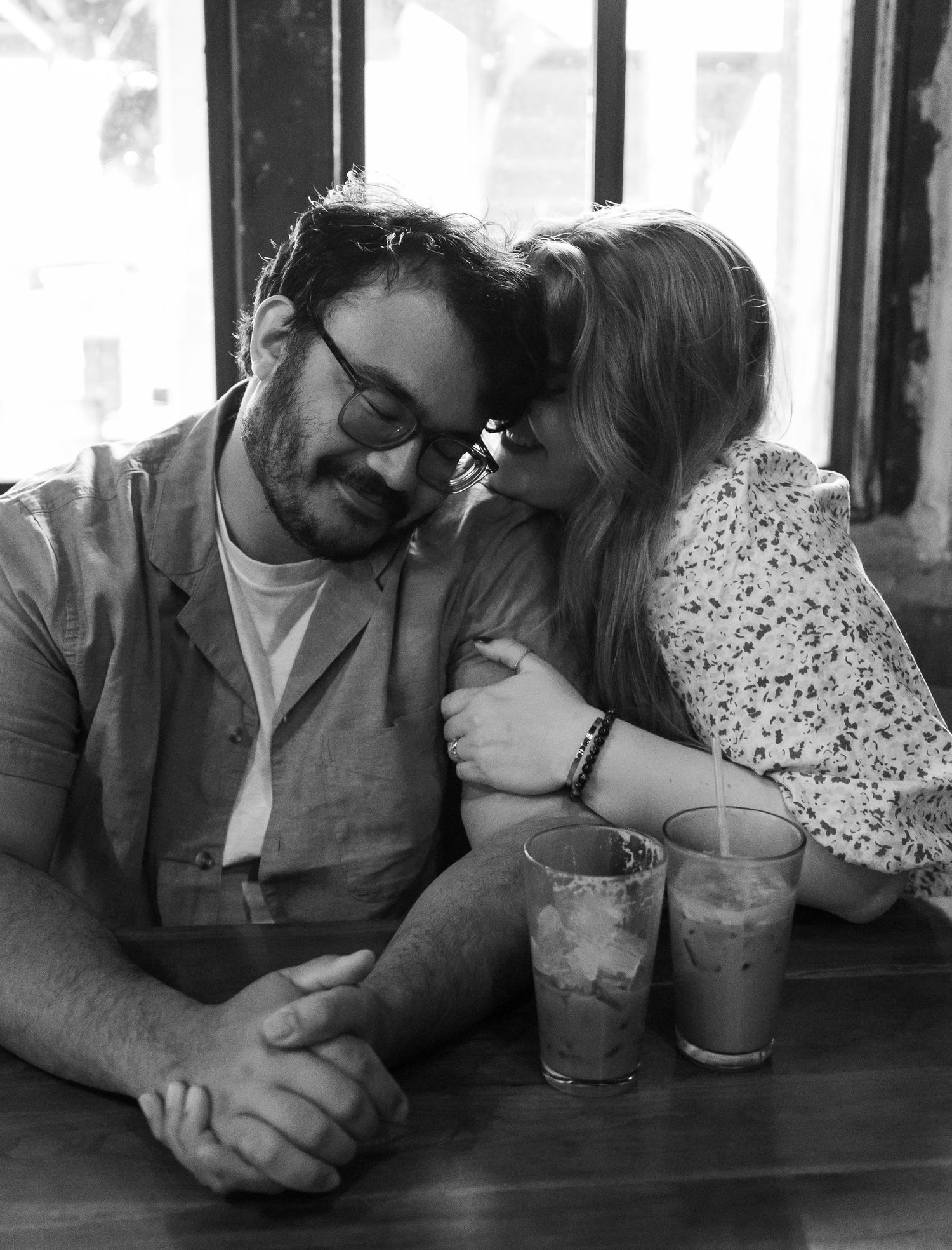 A romantic black and white photo sequence of a couple sharing drinks at a cafe table.