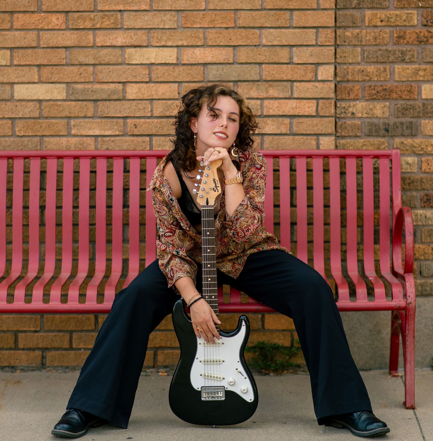 A series of four connected photos showing a person in black clothing sitting on a brick wall with a pink bench.
