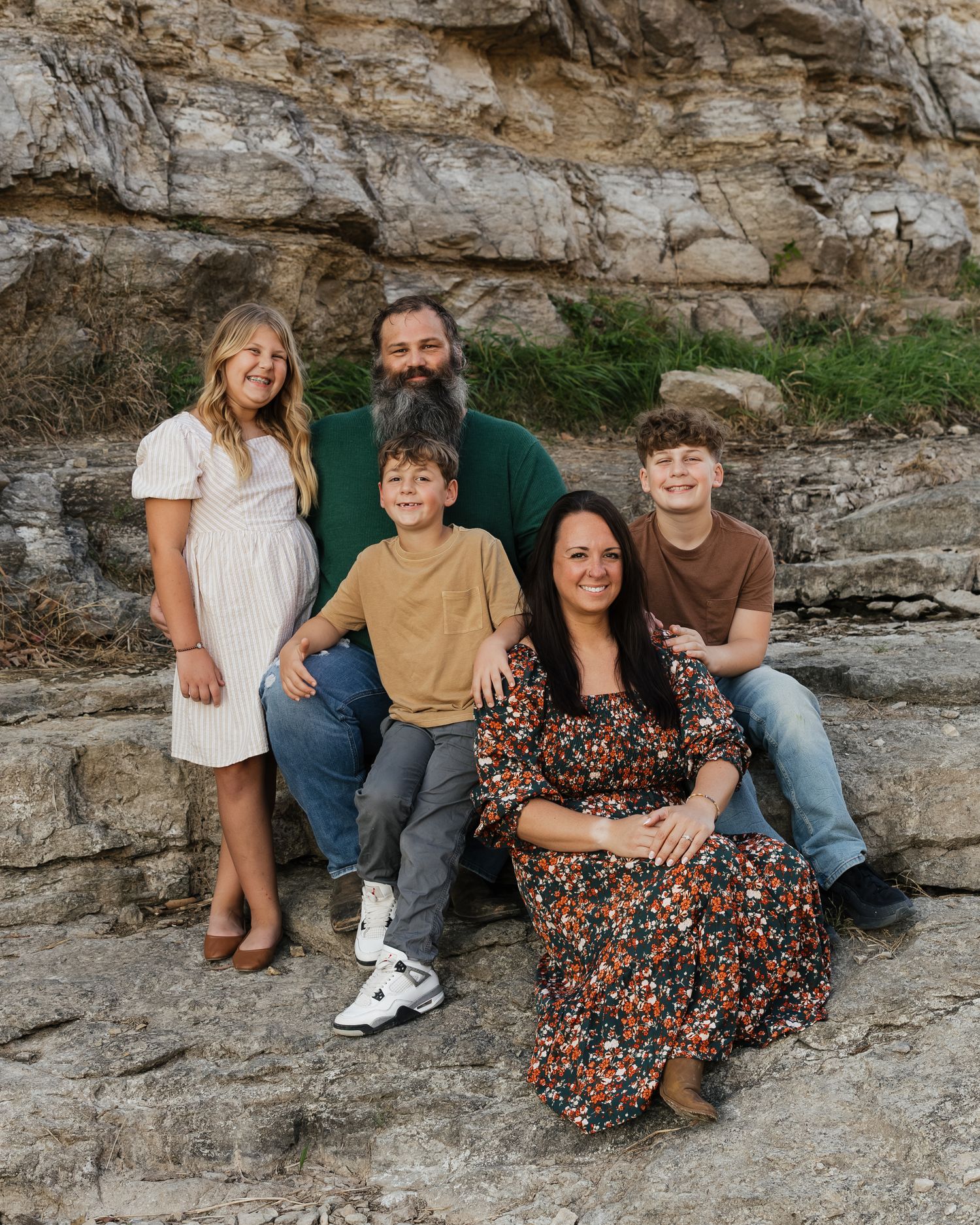 Group poses casually on rocky outcrop during outdoor family photo session.